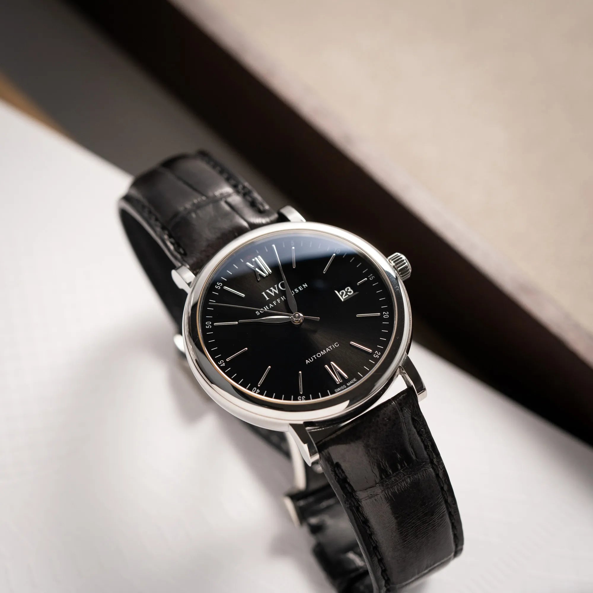 Produktfotografie der IWC Portofino 40 Automatik Armbanduhr mit schwarzem Zifferblatt am schwarzen Lederband