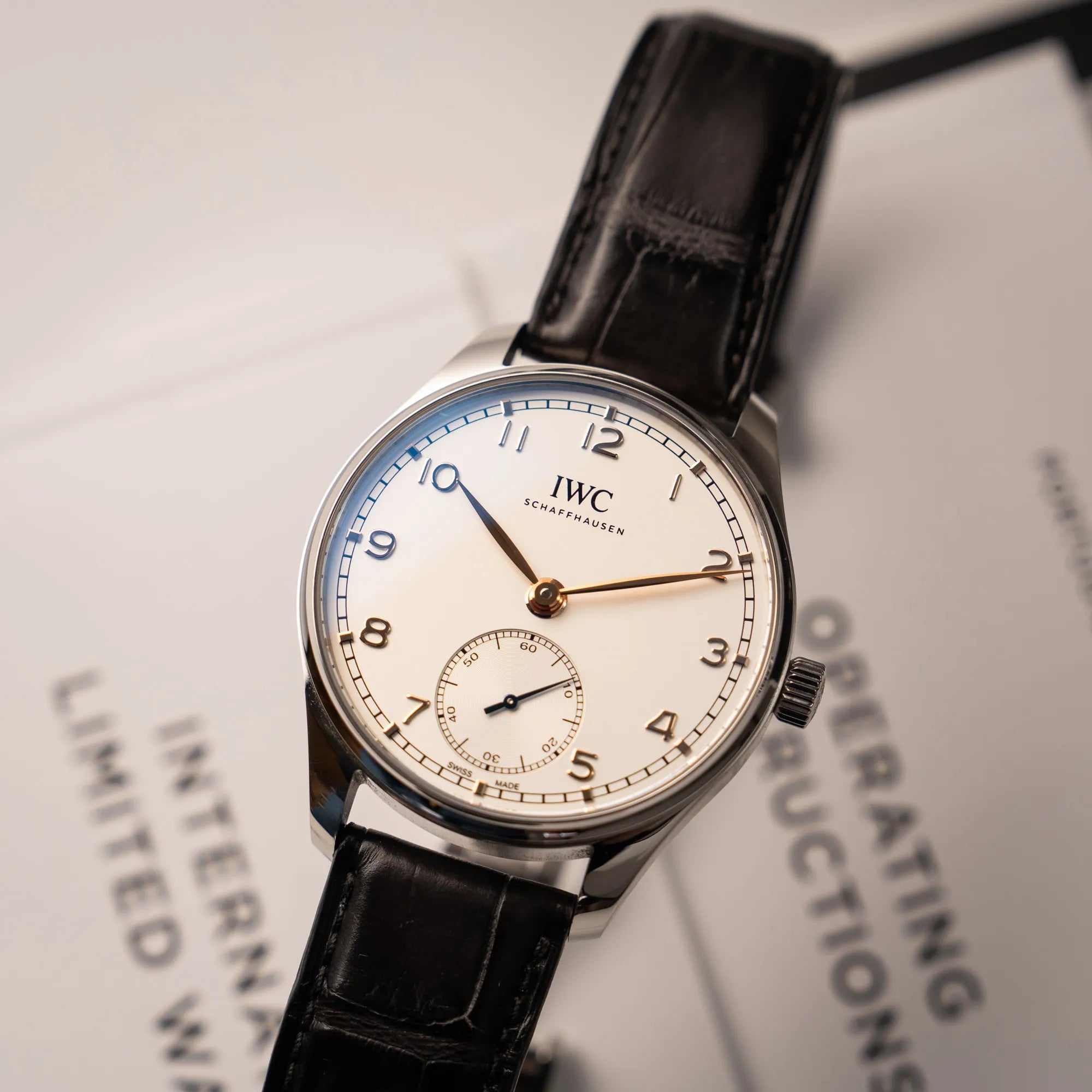 Produktfotografie als Titelbild für die IWC Portugieser 40 Automatik IW358303 mit weißem Zifferblatt und roségoldenen Zeiger- und Index-Details am schwarzen Lederband