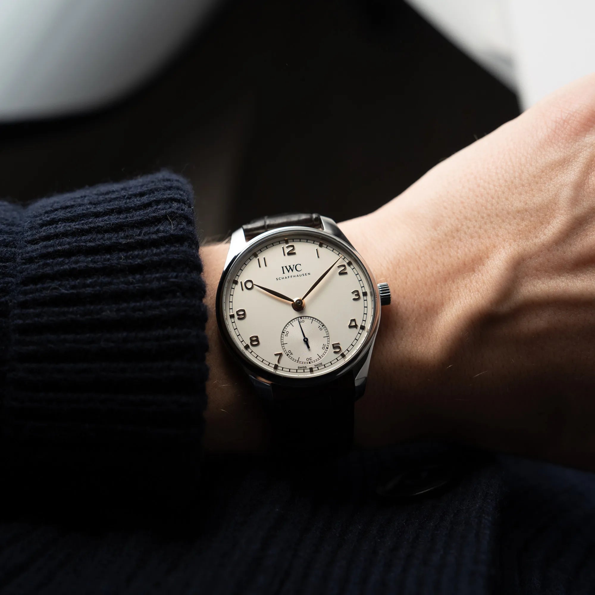 Wristshot mit der IWC Portugieser 40 Automatik IW358303 mit weißem Zifferblatt und roségoldenen Zeiger- und Index-Details am schwarzen Lederband