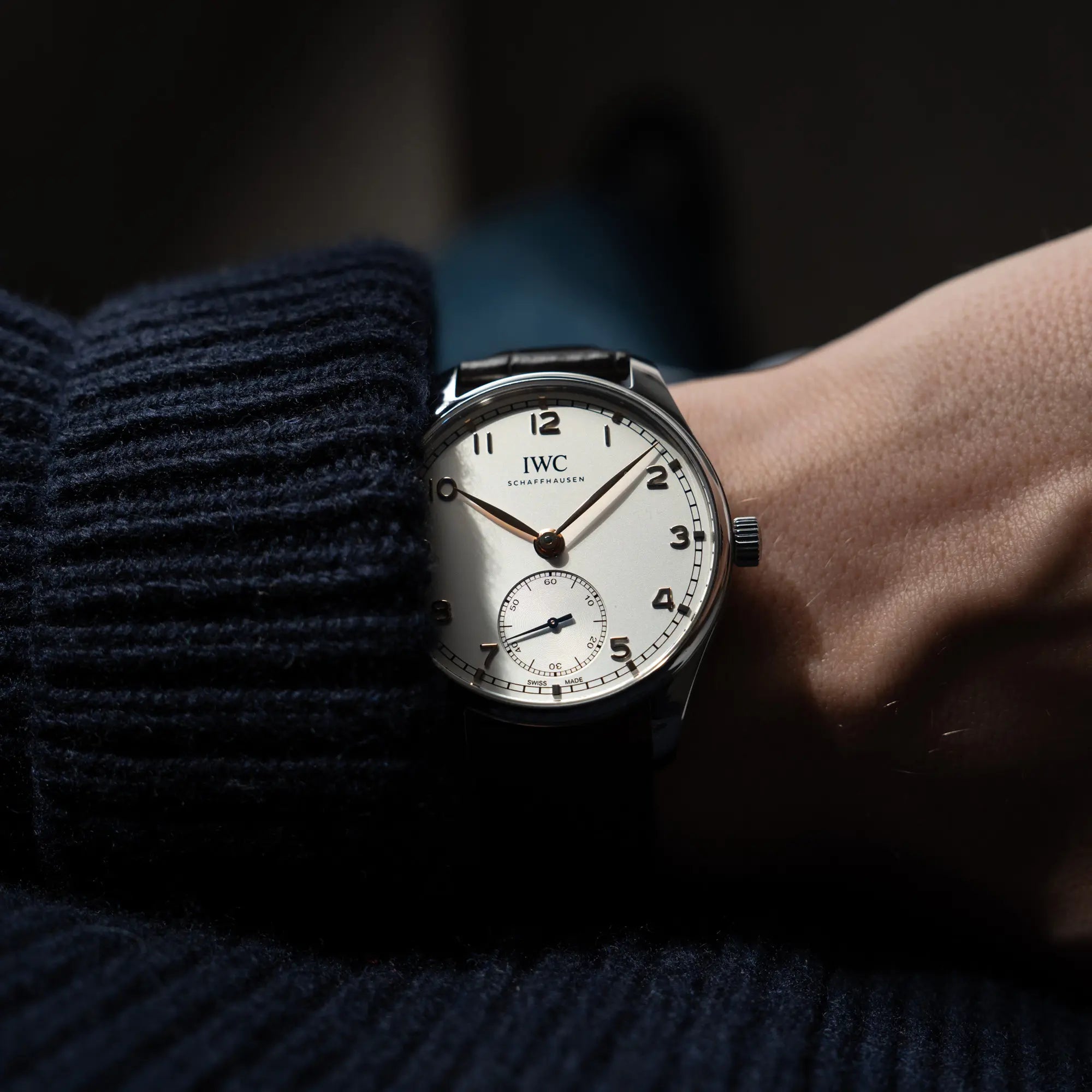 Mann trägt die IWC Portugieser 40 Automatik IW358303 mit weißem Zifferblatt und roségoldenen Zeiger- und Index-Details am schwarzen Lederband für einen Wristshot an seinem Handgelenk