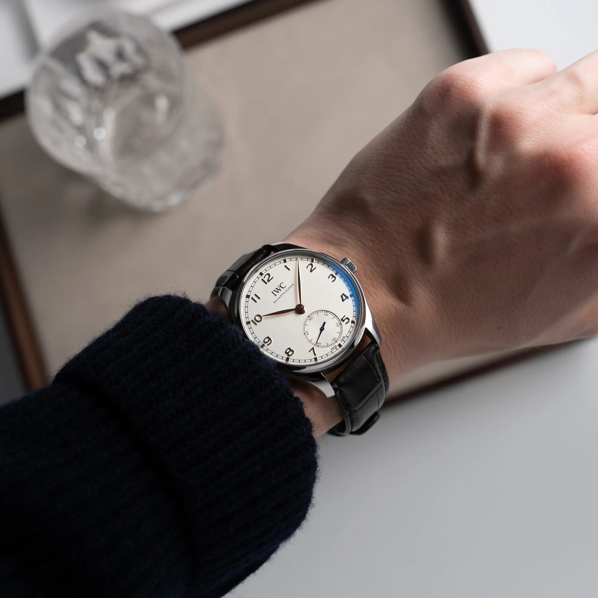 Mann trägt die IWC Portugieser 40 Automatik IW358303 mit weißem Zifferblatt und roségoldenen Zeiger- und Index-Details am schwarzen Lederband an seinem Wristshot