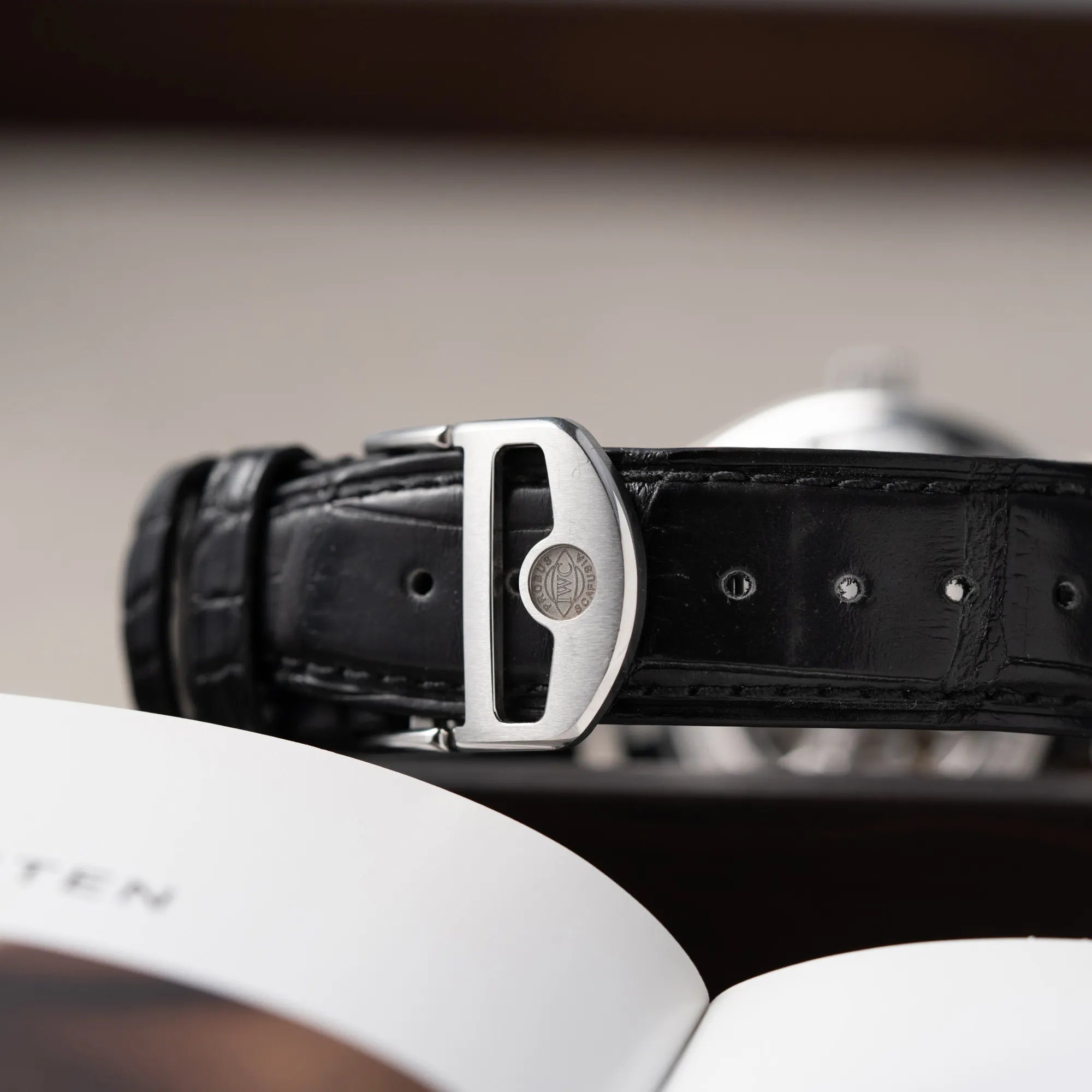 Detailaufnahme der geschlossenen Faltschließe an der IWC Portugieser 40 Automatik IW358303 mit weißem Zifferblatt und roségoldenen Zeiger- und Index-Details am schwarzen Lederband