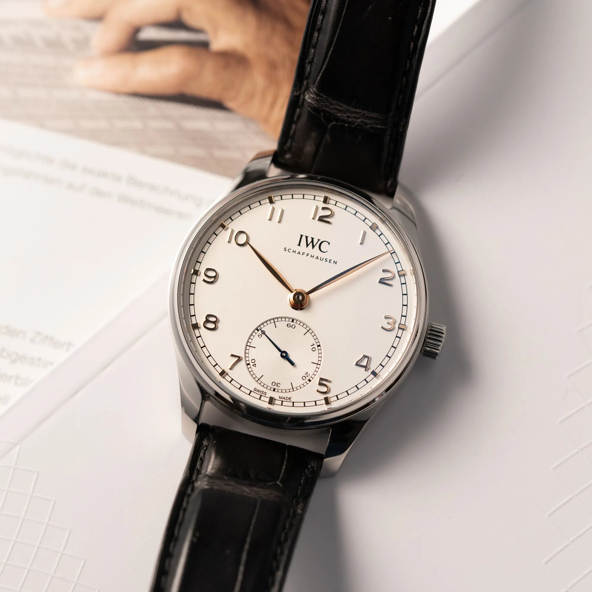 Produktfotografie zeit den Uhrenkopf der IWC Portugieser 40 Automatik IW358303 mit weißem Zifferblatt und roségoldenen Zeiger- und Index-Details am schwarzen Lederband