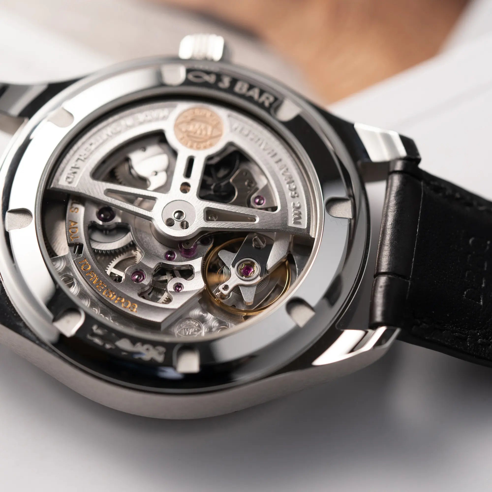 Detailaufnahme des Uhrwerks durch den Sichtboden von der IWC Portugieser 40 Automatik IW358303 mit weißem Zifferblatt und roségoldenen Zeiger- und Index-Details am schwarzen Lederband