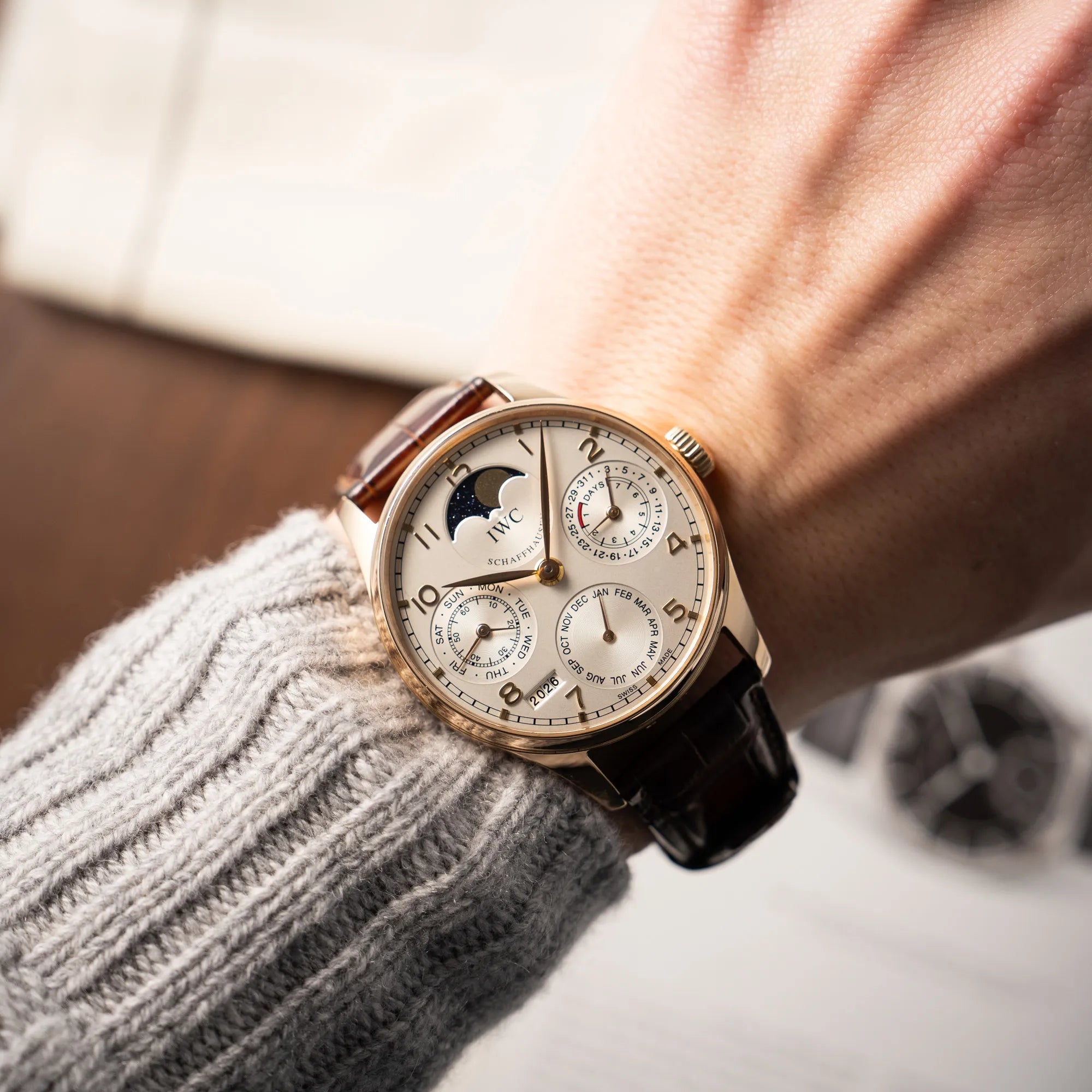 Mann trägt den Portugieser Ewiger Kalender IW502213 von IWC in einem 42mm-Rosegold-Gehäuse am braunem IWC Lederband mit einem sanften weißem Zifferblatt an seinem Handgelenk