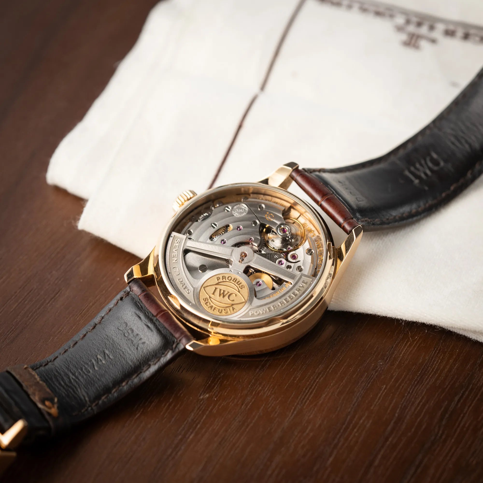 Produktfotografie des Portugieser Ewiger Kalender IW502213 von IWC in einem 42mm-Rosegold-Gehäuse am braunem IWC Lederband mit einem sanften weißem Zifferblatt zeigt den Gehäuseboden