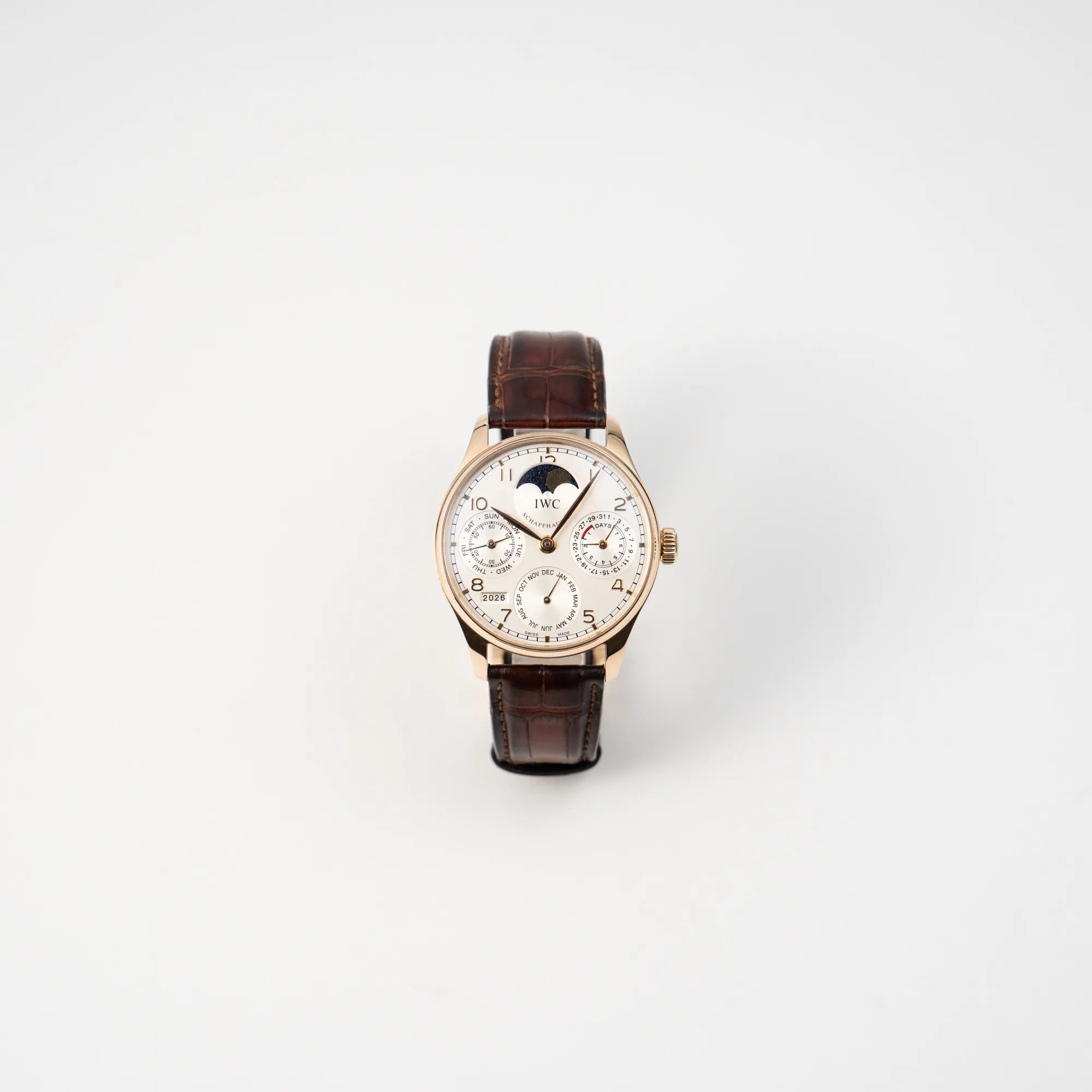 Frontale Ansicht des Portugieser Ewiger Kalender IW502213 von IWC in einem 42mm-Rosegold-Gehäuse am braunem IWC Lederband mit einem sanften weißem Zifferblatt