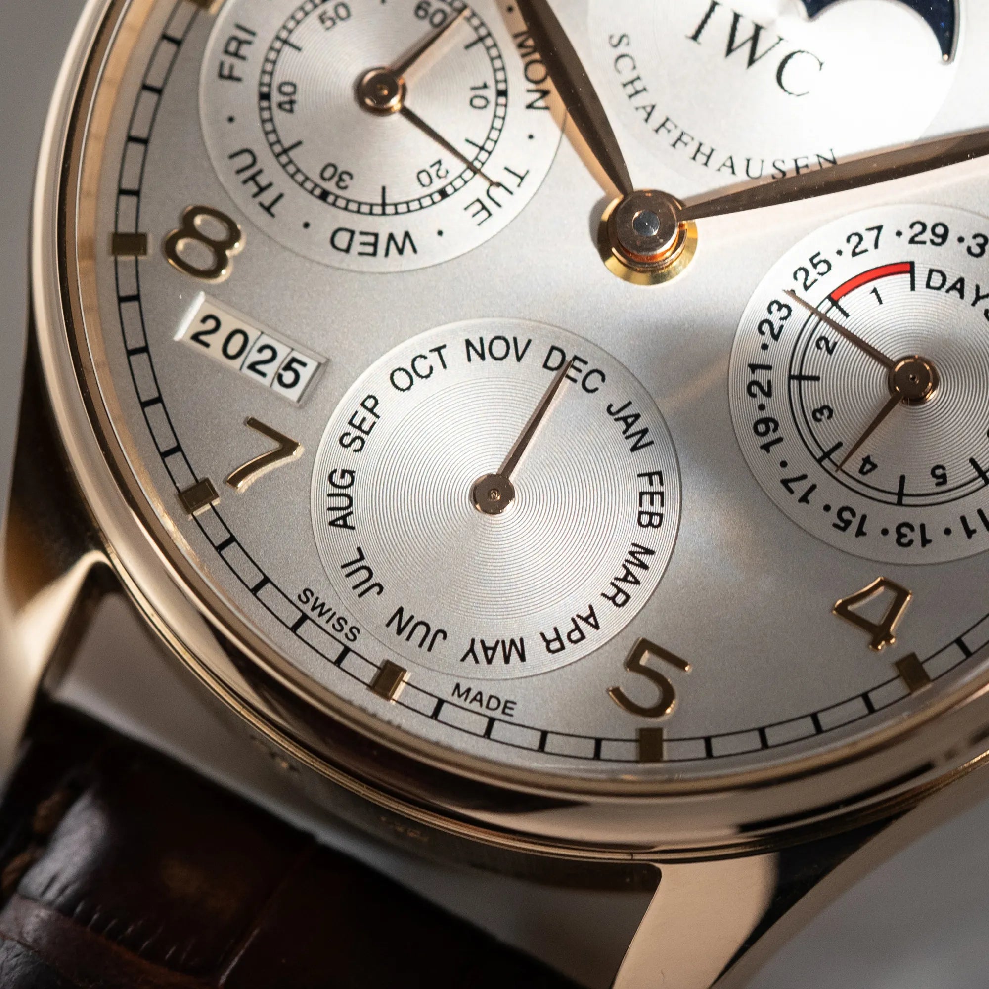 Makroaufnahme dr Monatsanzeige des Portugieser Ewiger Kalender IW502213 von IWC in einem 42mm-Rosegold-Gehäuse am braunem IWC Lederband mit einem sanften weißem Zifferblatt