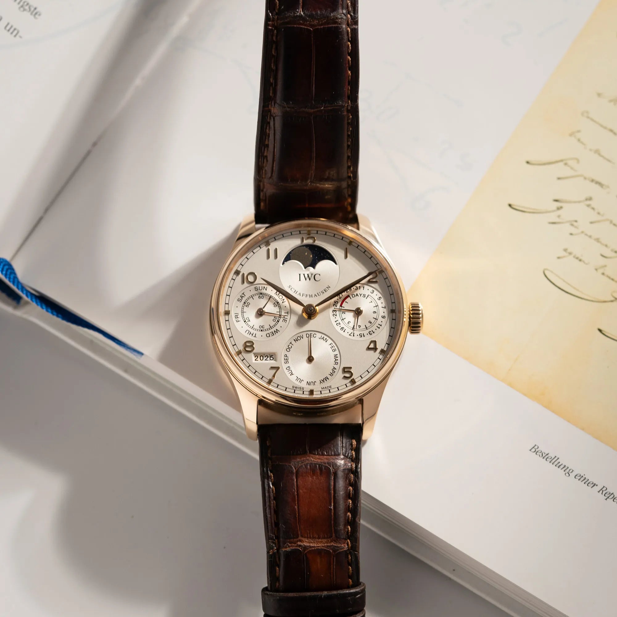 Produktfoto des Portugieser Ewiger Kalender IW502213 von IWC in einem 42mm-Rosegold-Gehäuse am braunem IWC Lederband mit einem sanften weißem Zifferblatt