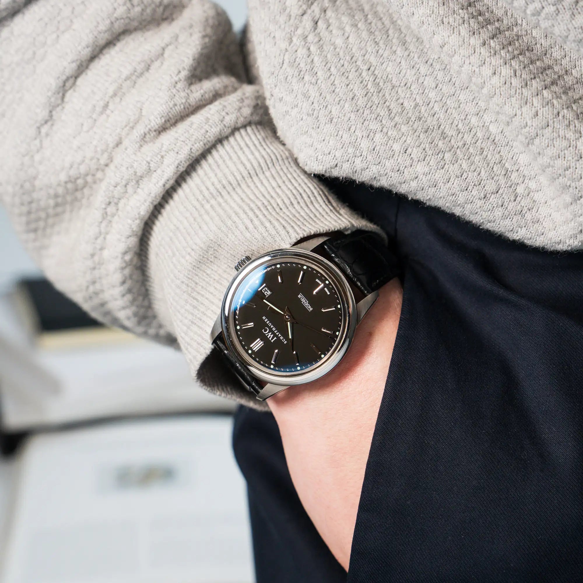 Mann trägt die IWC Schaffhausen Uhr "Ingenieur" mit der Referenz IW323301 mit schwarzem Zifferblatt an seinem Handgelenk, während die Hand in seiner Hosentasche steckt