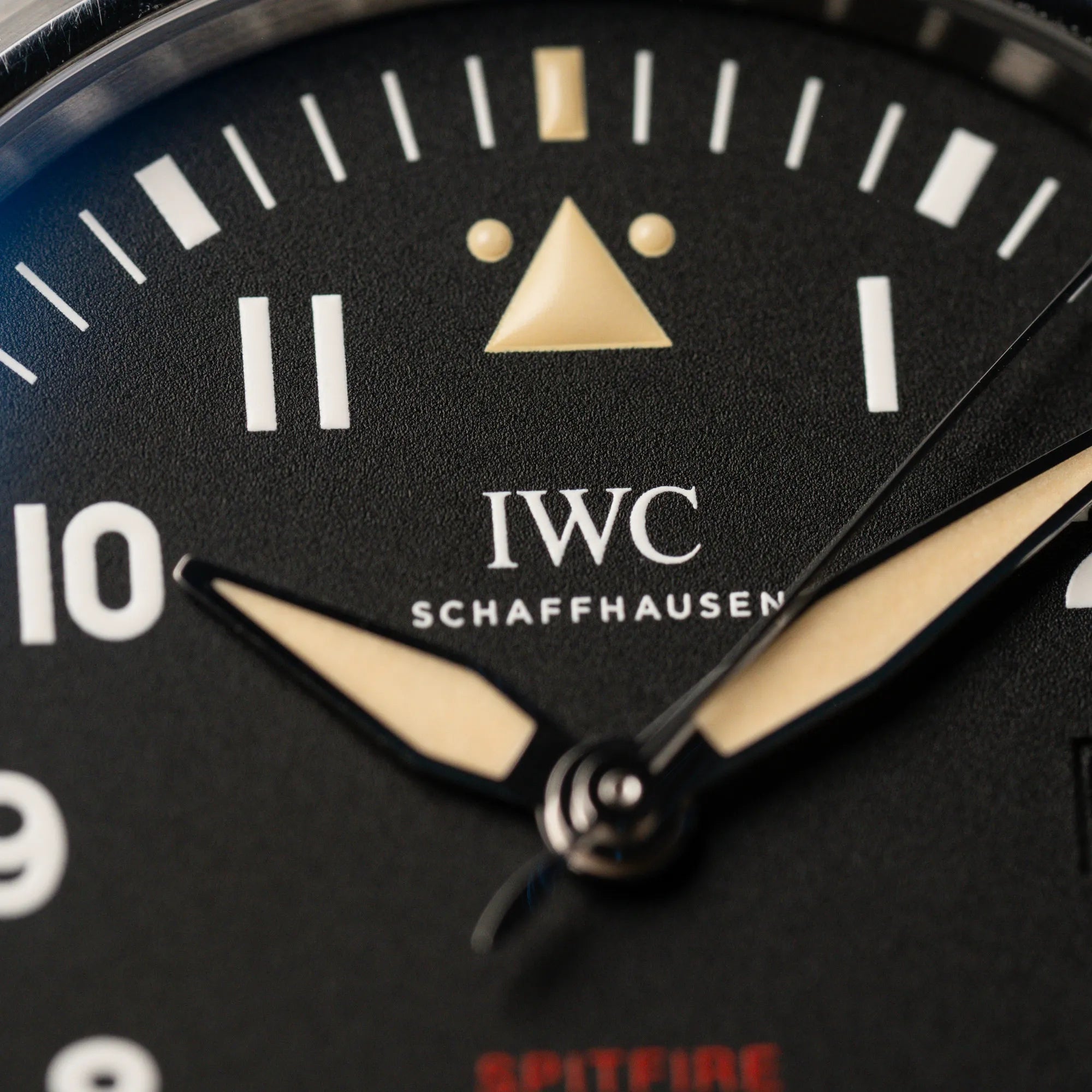 Makroaufnahme der IWC Pilotenuhr Automatic Spitfire IW326803 mit schwarzen Zifferblatt  mit Fokus auf dem IWC Schaffhausen Schriftzug und den beigen Highlights als Zeiger und auf 12 Uhr