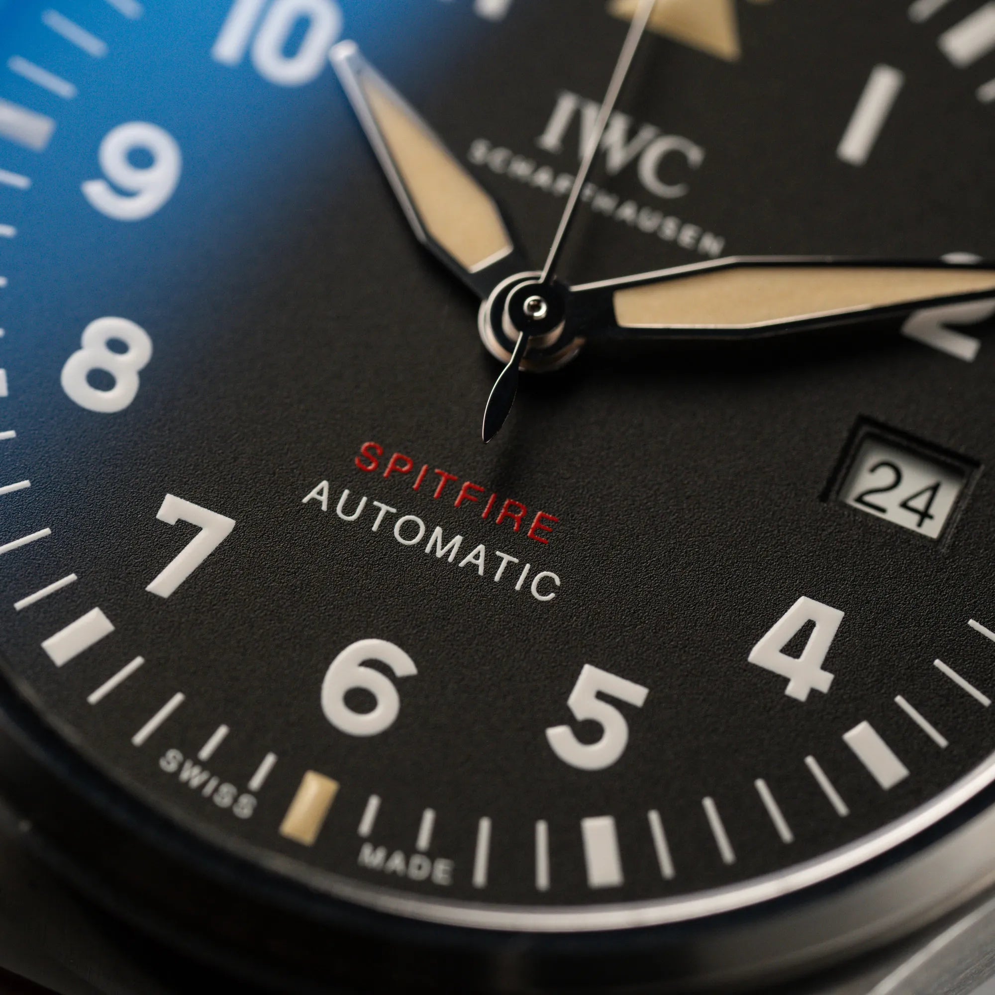 Makroaufnahme der IWC Pilotenuhr Automatic Spitfire IW326803 mit schwarzen Zifferblatt an einem braunem Lederband mit Fokus auf dem rot-weißen "Spitfire Automatic" Schriftzug