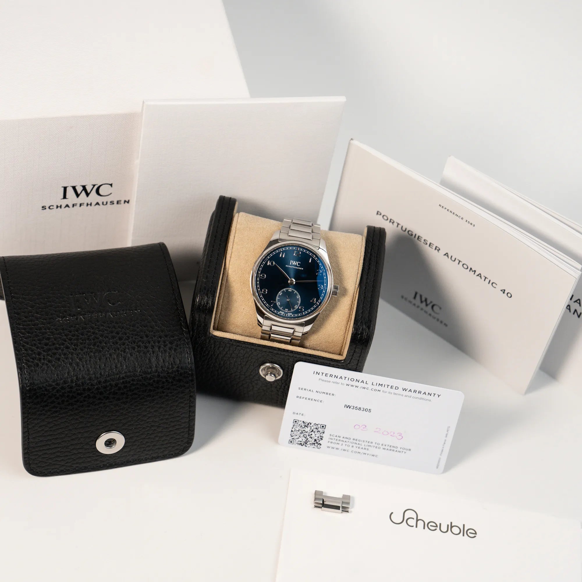 Produktfotografie der IWC Armbanduhr Portugieser 40 Automatic mit blauem Zifferblatt am IWC-Edelstahlband zusammen mit dem Lieferumfang