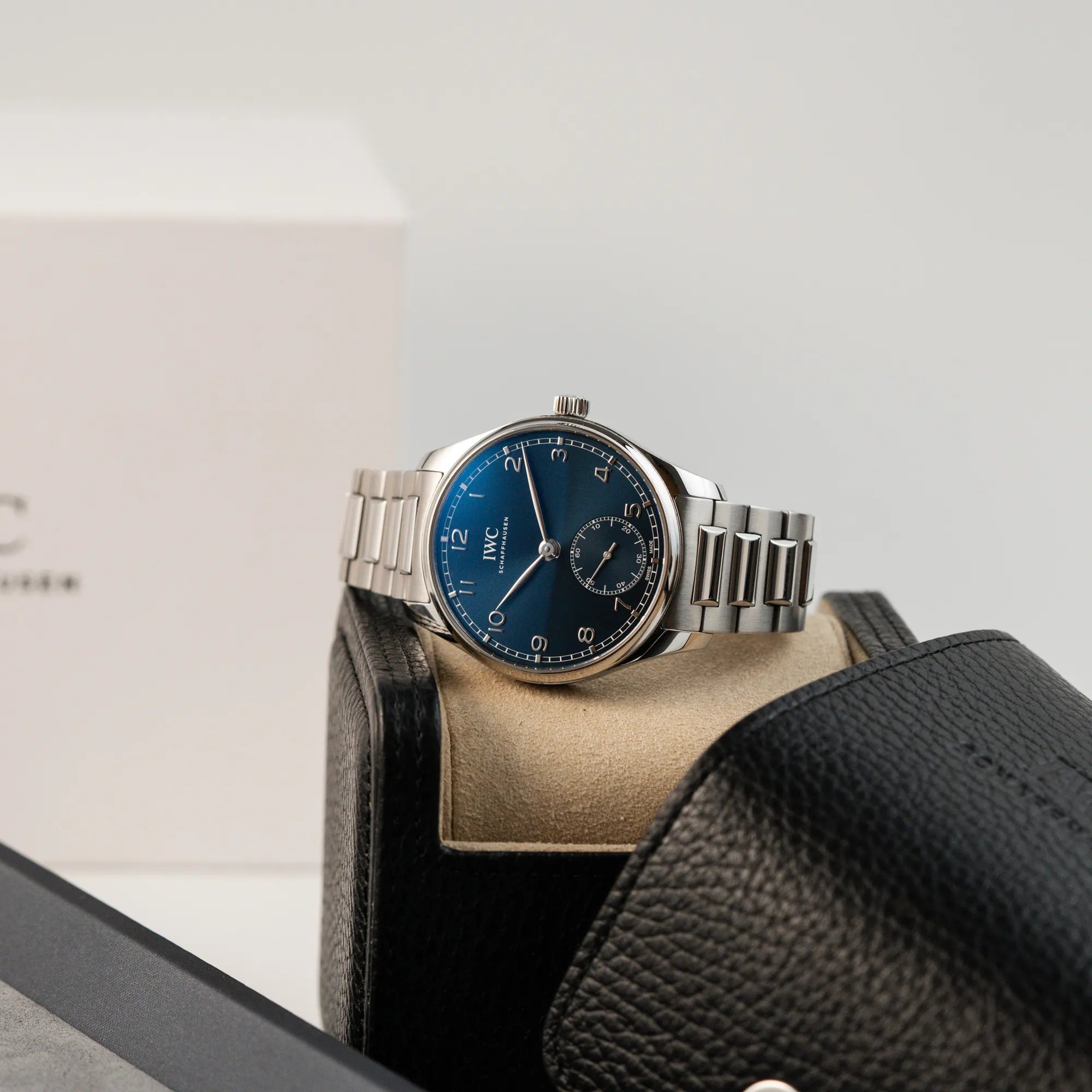 Produktfotografie der IWC Armbanduhr Portugieser 40 Automatic mit blauem Zifferblatt am IWC-Edelstahlband, während die Uhr auf dem IWC-Leder-Etui liegt