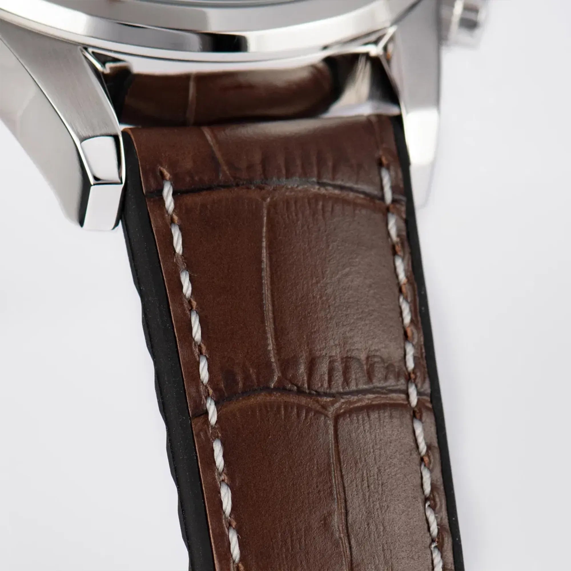 Detailaufnahme des Bandanstoßes der Jacques Lemans 1-2117W Chronograph-Armbanduhr für Herren mit einem anthrazitfarbenen Zifferblatt, roségoldfarbenen Ziegern und Edelstahl-Gehäuse an einem braunem Lederarmband mit einer groben Struktur und mit weißer Ziernaht 