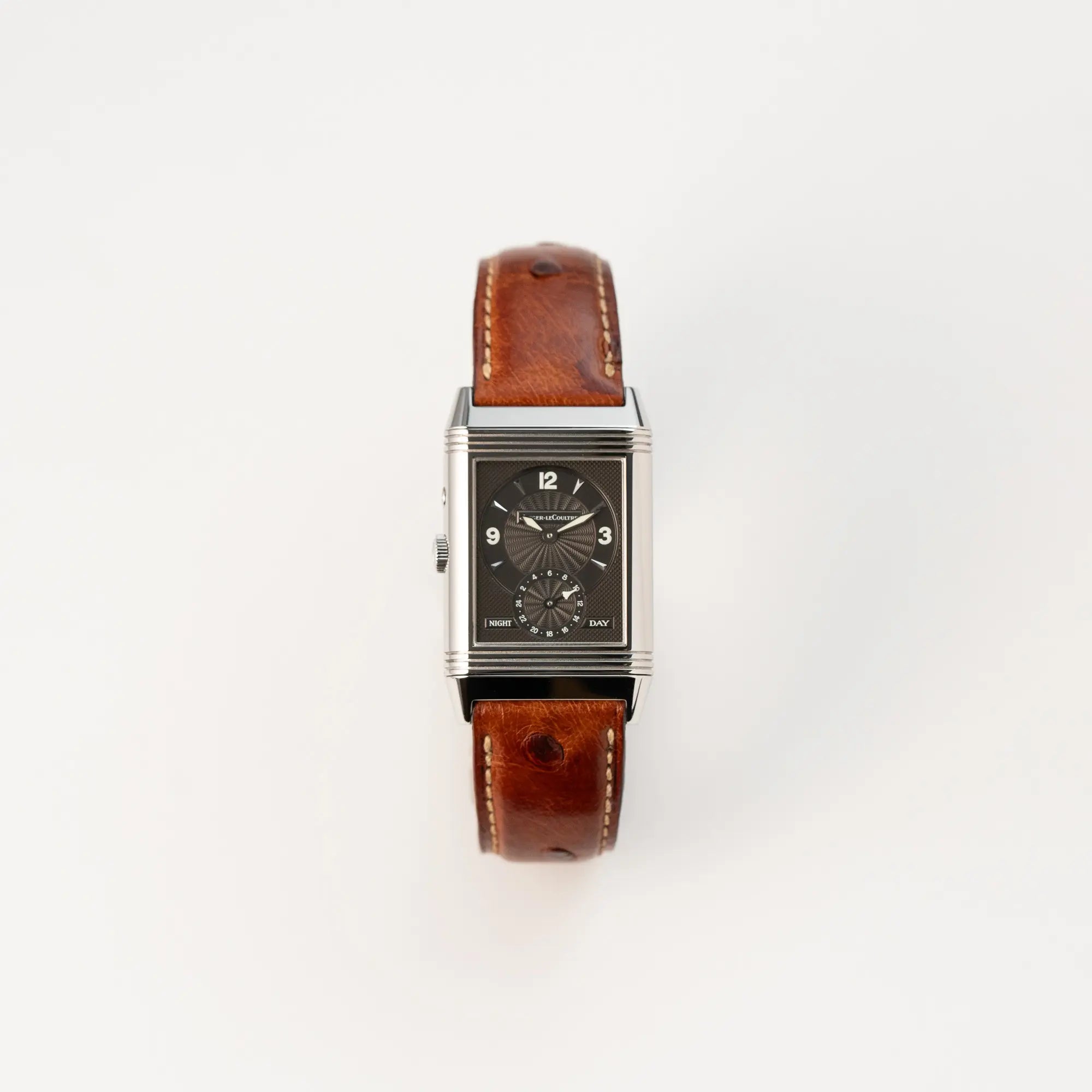 Frontale Ansicht der JLC Reverso Duoface 270.8.54 am braunen Lederband mit benutzem Reverso-Mechanismus und dem Night-and-Day-Zifferblatt