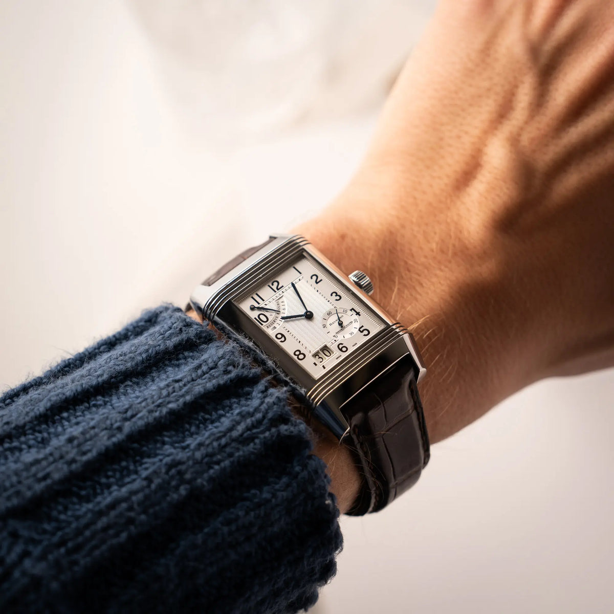 Mann trägt die Jaeger-LeCoultre Reverso Grande Date der Referenz 240.8.15 mit silberfarbenem Zifferblatt und Großdatums-Anzeige, kleiner Sekunde und Gangreserve-Anzeige am braunen Lederband an seinem Handgelenk