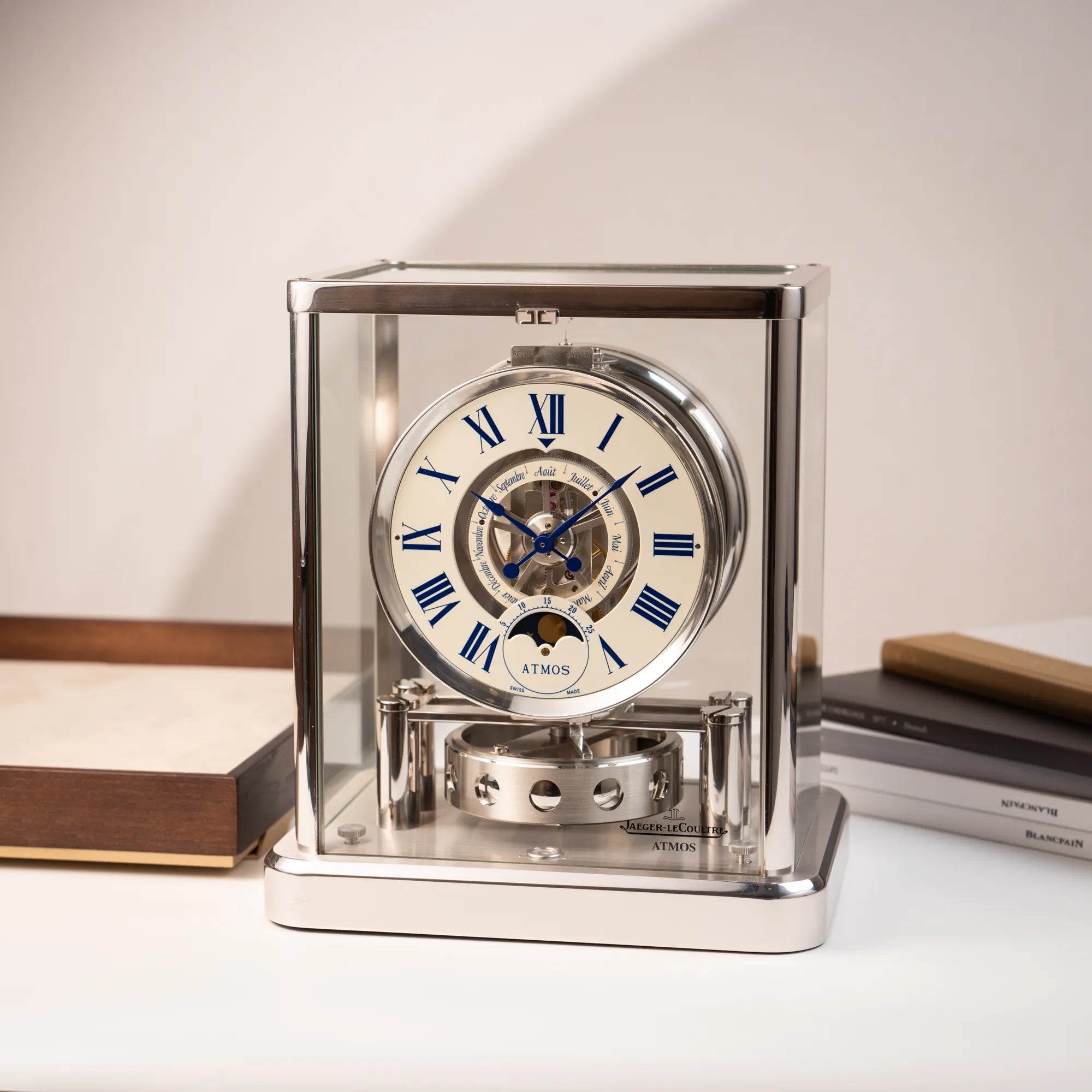 Produktfotografie der Jaeger-LeCoultre Atmos Mondphase Tischuhr in rhodiniertem Stahl mit weißem Zifferblatt und blauen römischen Indizes