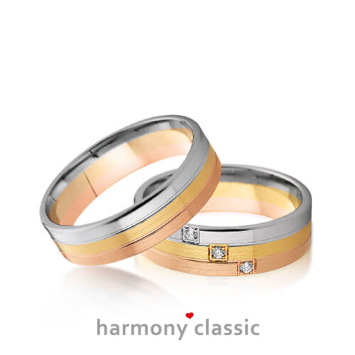 Produktfotografie des Trauringpaars Harmony Classic in Rosegold, Gelbgold und Weißgold  mit jeweils einem Diamanten pro Goldstreifen im Damenring