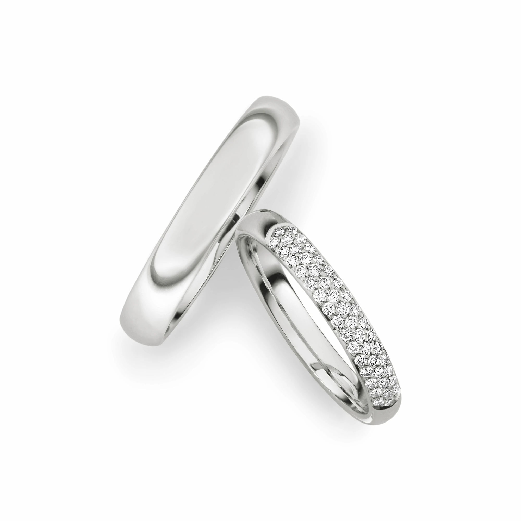 Produktfotografie des weissgoldenen Max Kemper Trauringpaars mit polierter Oberflächenstruktur und einer Vielzahl an kleinen in drei Reihen angeordneten Diamanten als Verzierung des Damenrings