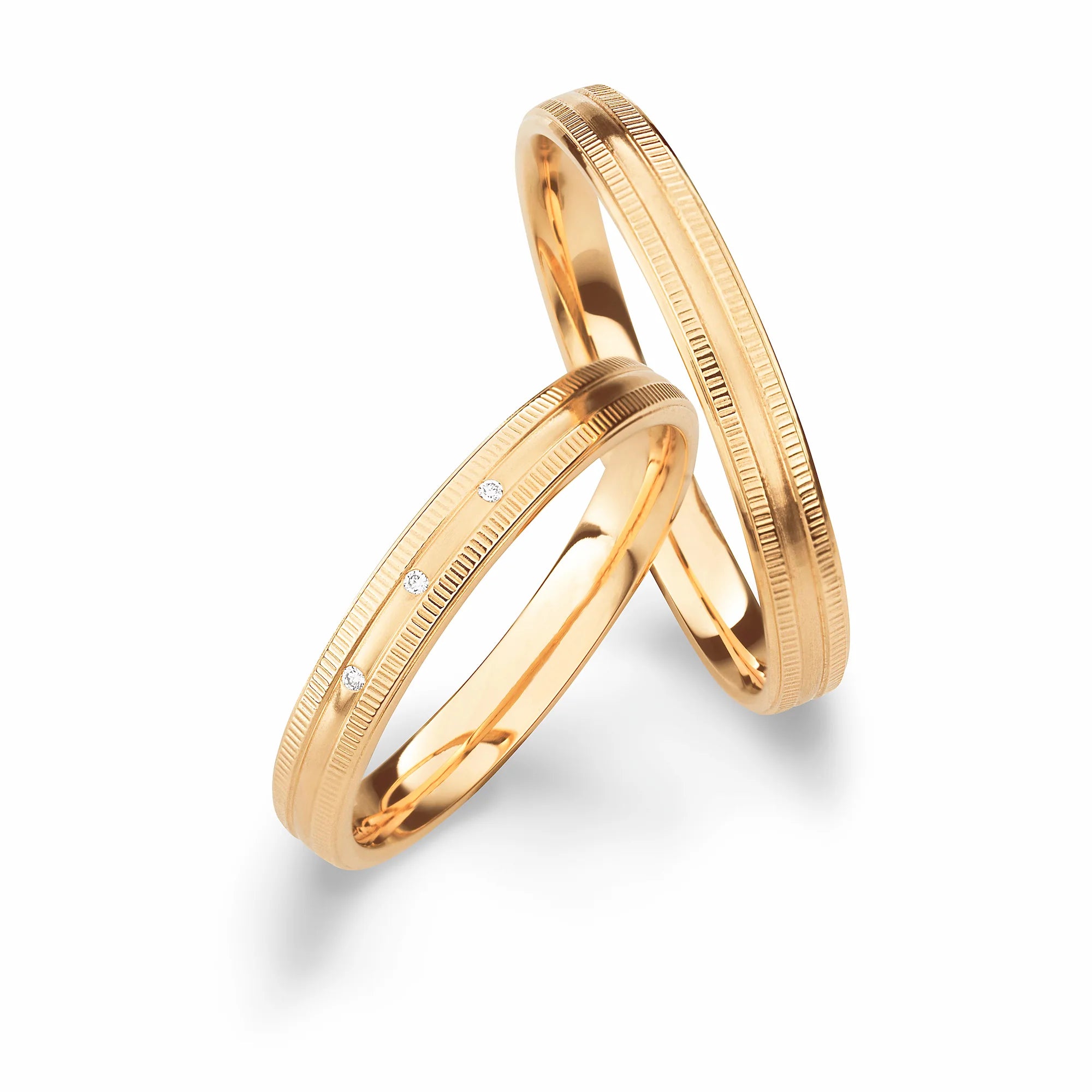 Produktfotografie des gelbgoldenen Max Kemper Trauringpaars mit einer teilweise kannelierten Oberflächenstruktur als Design-Element und mit Diamanten als Verzierung im Damenring