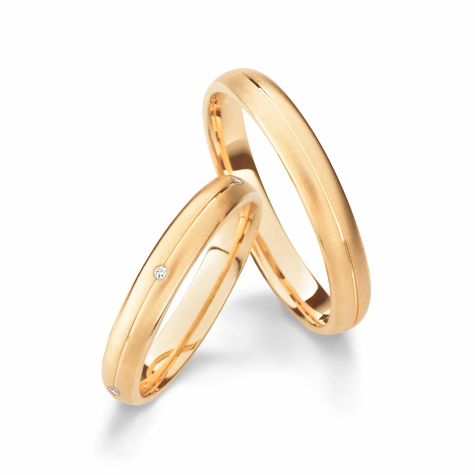 Produktfotografie des gelbgoldenen Max Kemper Trauringpaars mit einer zentralen Nut und Diamanten im Damenring