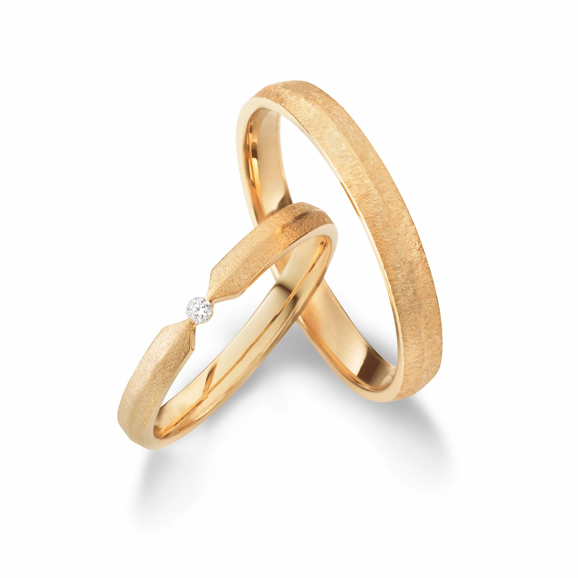 Produktfotografie des gelbgoldenen Max Kemper Trauringpaars in gebürsteter Oberflächenstruktur mit einer zentralen Fase, sowie einem frei gefassten Brillanten