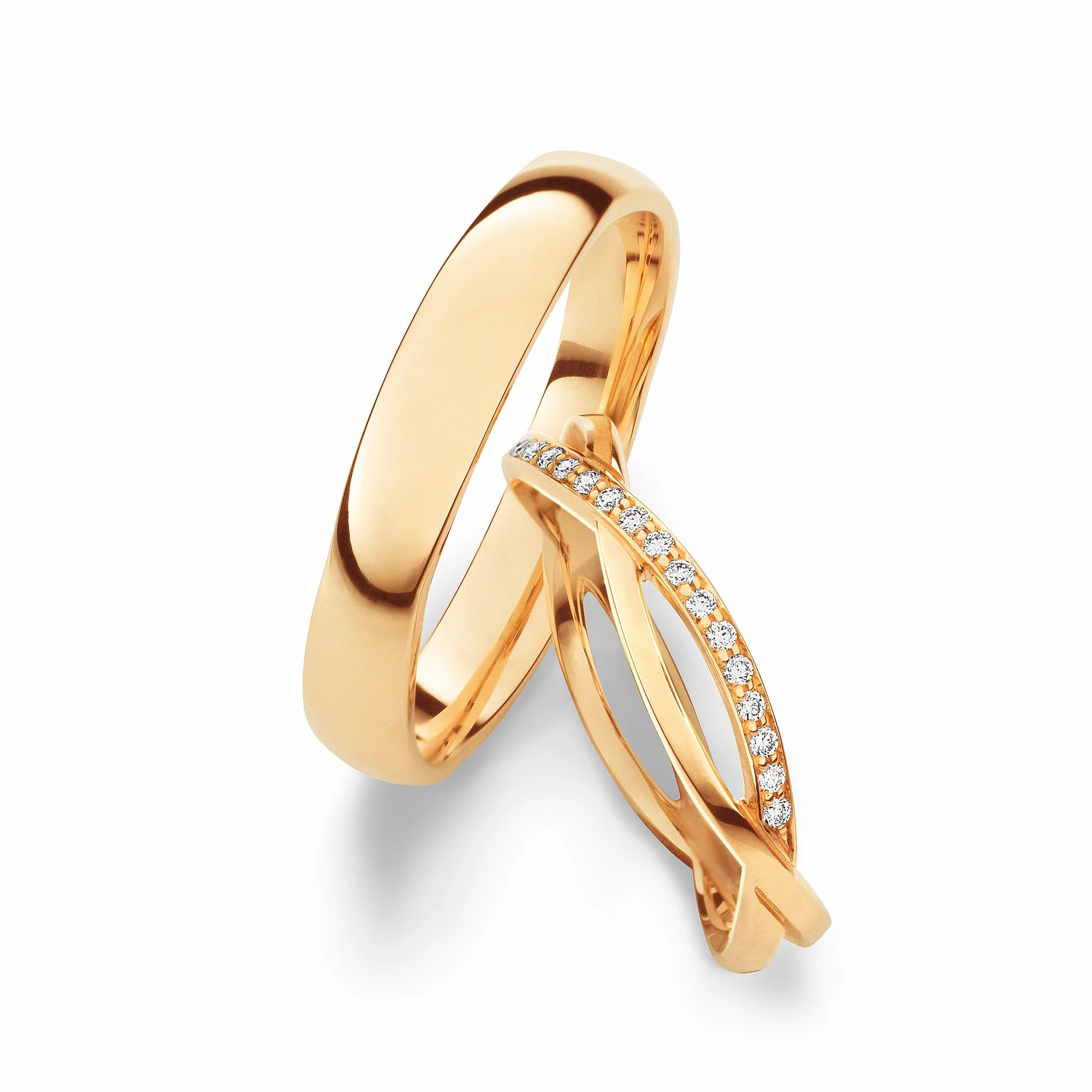 Produktfotografie des gelbgoldenen Max Kemper Trauringpaars mit einem simplen hochglanzpoliertem Männerring und einem Damenring, bestehend aus zwei ineinander verschmelzenden Ringschienen, wovon eine mit Diamanten besetzt ist