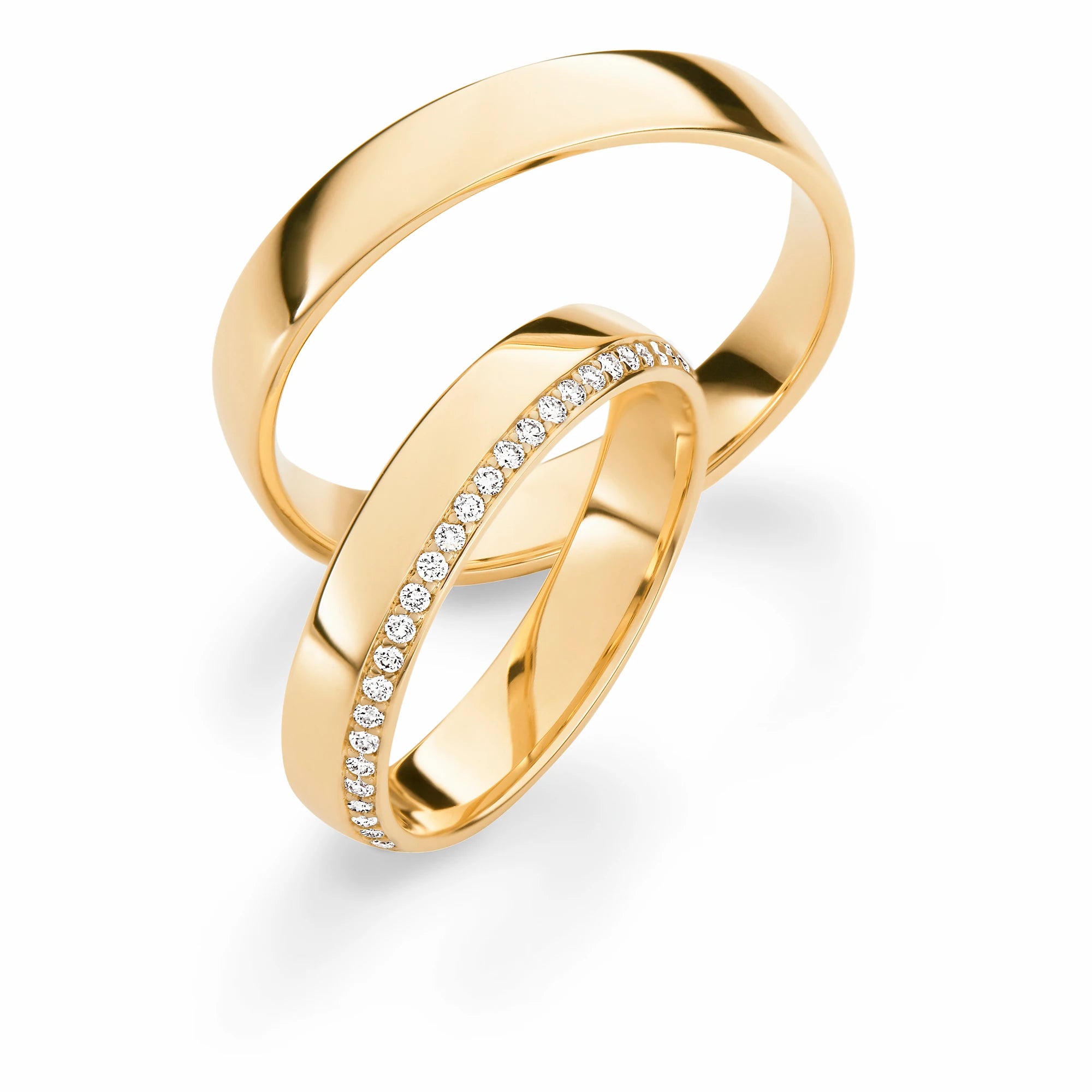 Produktfotografie des gelbgoldenen Max Kemper Trauringpaars mit polierter Oberfläche und einem asymmetrisch platzierten Diamantkranz als Verzierung des Damenrings