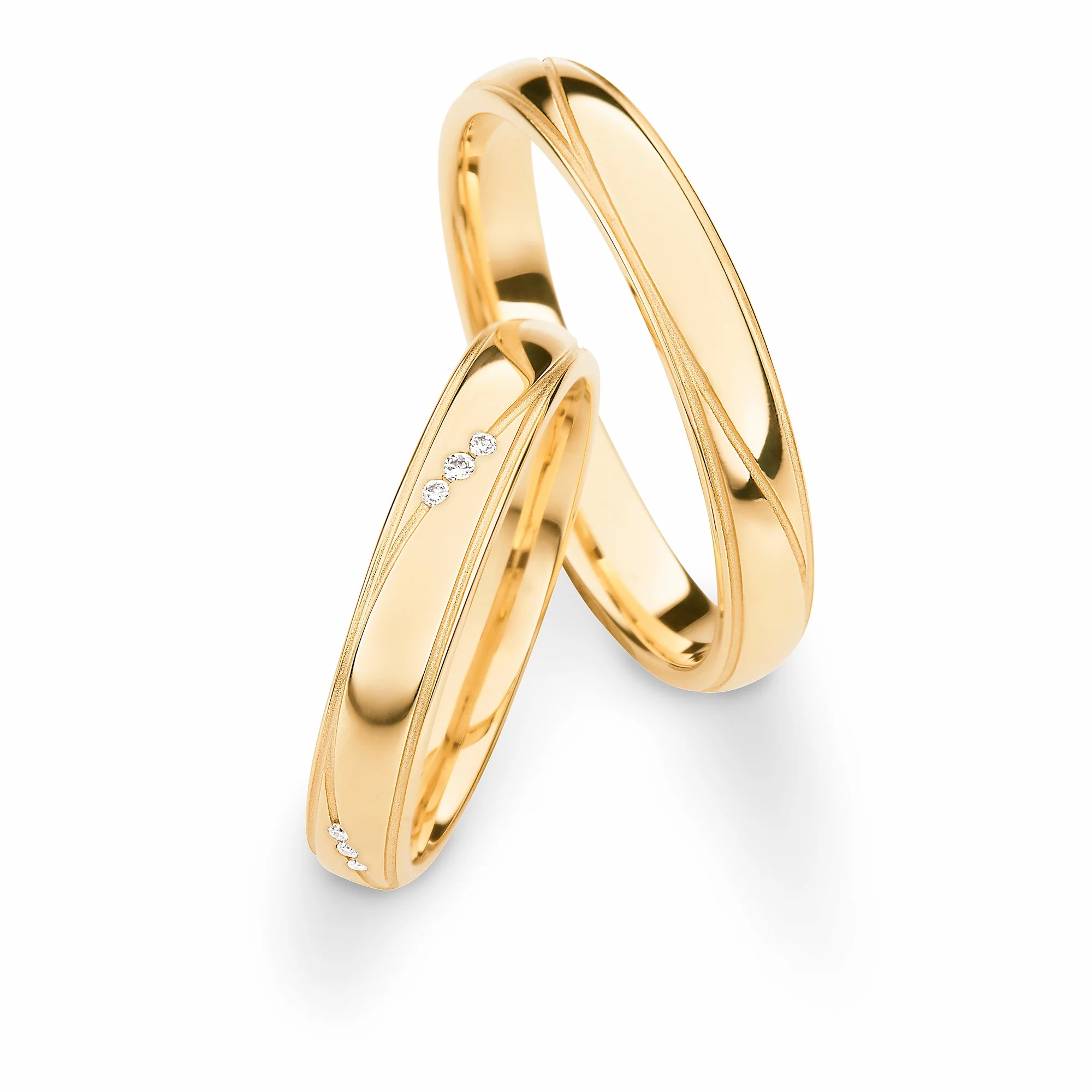 Produktfotografie des gelbgoldenen Max Kemper Trauringpaars mit einer geschwungenen eingravierten Linie 