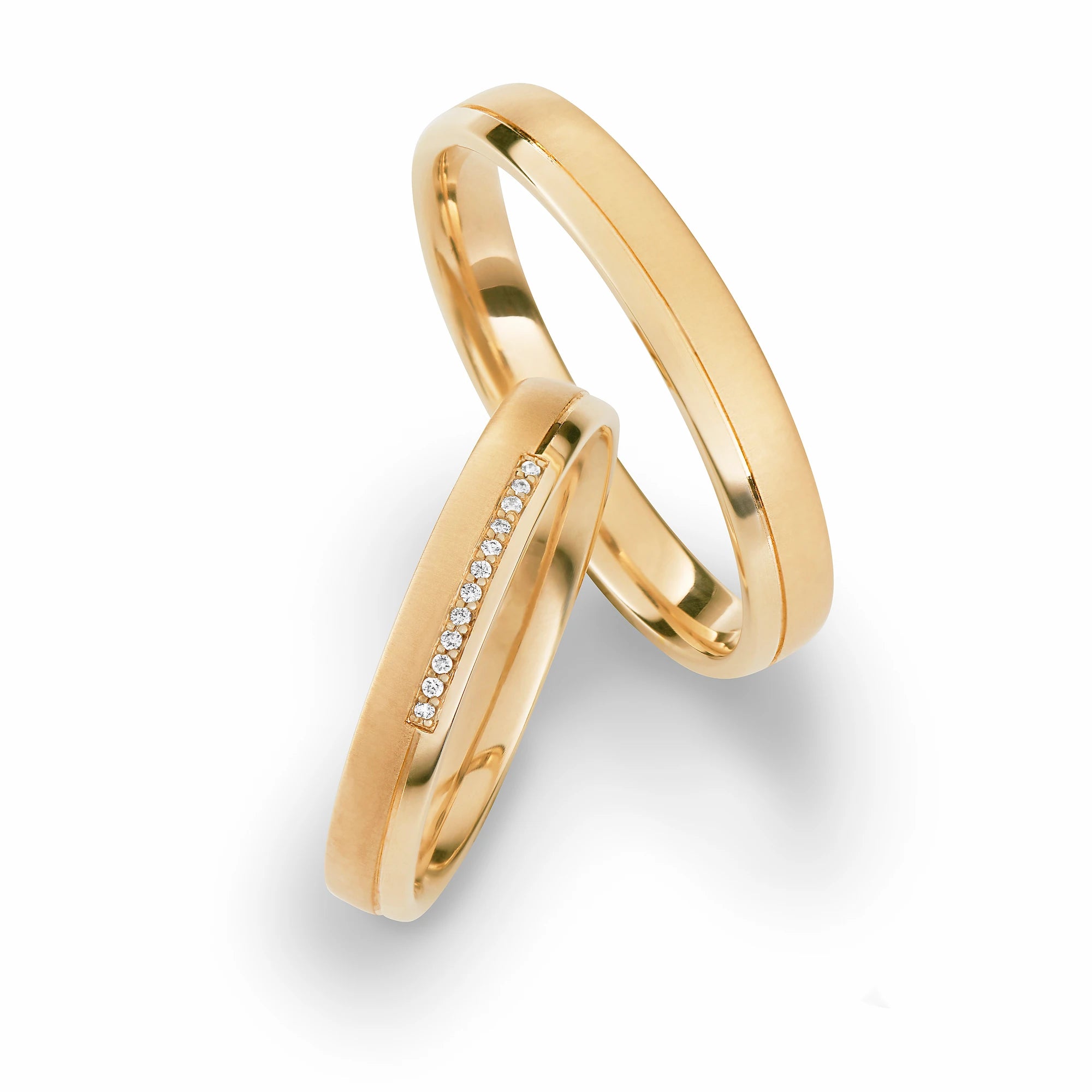 Produktfotografie des gelbgoldenen Max Kemper Trauringpaars mit 2 verschiedenen Oberflächendetails, hochglanzpoliert und angeraut, und einer Diamant-Reihe aus 12 Brillanten als Verzierung des Damenrings