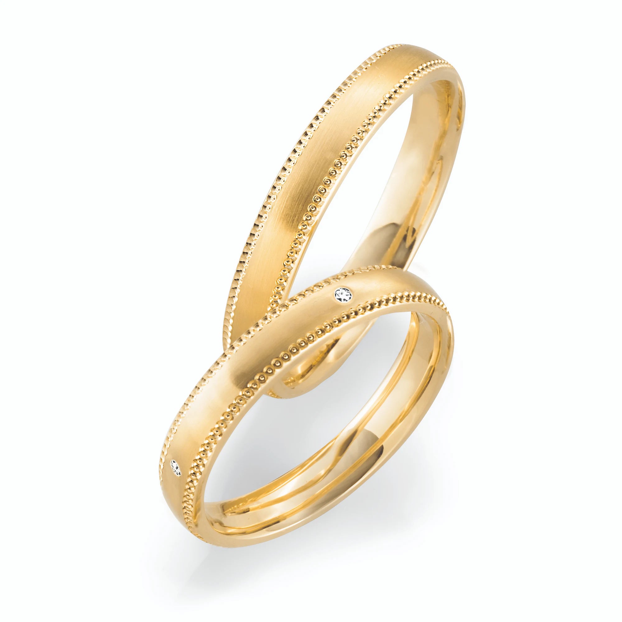 Produktfotografie des gelbgoldenen Max Kemper Trauringpaars mit feiner Verzierung und Diamanten im Damenring