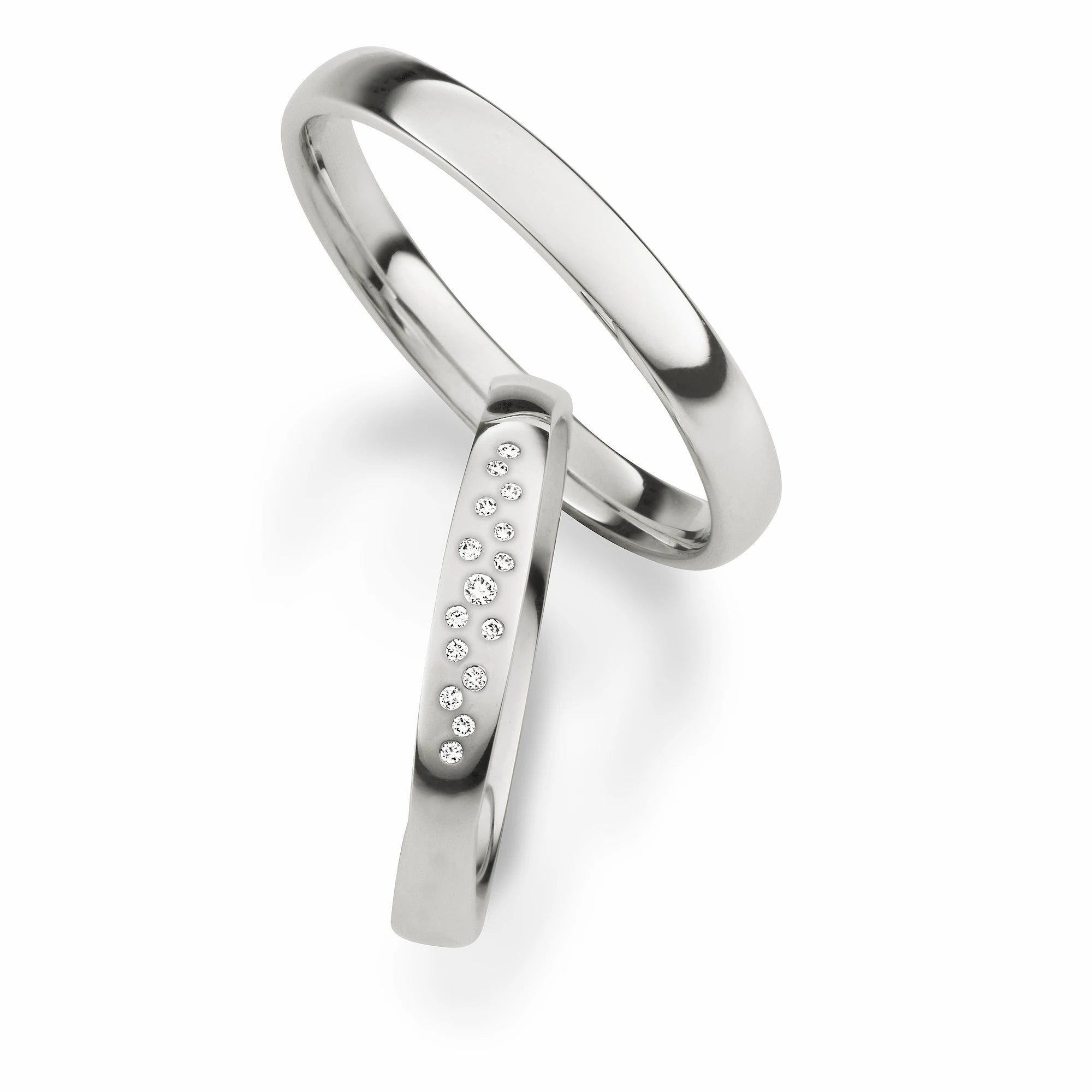 Produktfotografie des weißgoldenen Max Kemper Trauringpaars mit einer glatten polierten Oberflächenstruktur und speziell für den Damenring eingefassten mehreren kleinen Diamanten