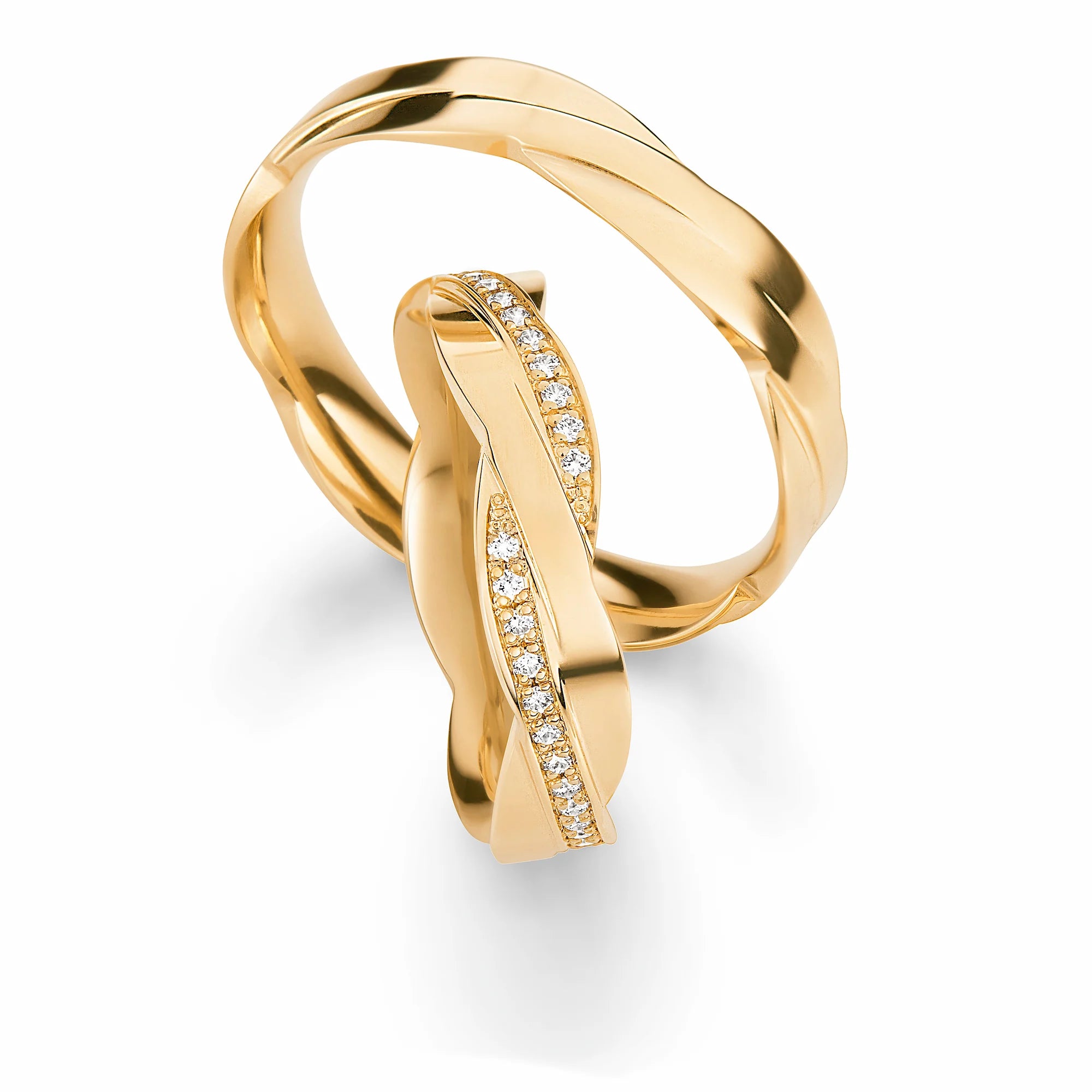 Produktfotografie des gelbgoldenen Max Kemper Trauringpaars mit einer einzigartigen Form der Ringschiene, die an zwei ineinander verschmelzende Ringe erinnert, mit einer polierten Oberfläche  und speziell für den Damenring eingefassten Diamant-Schienen