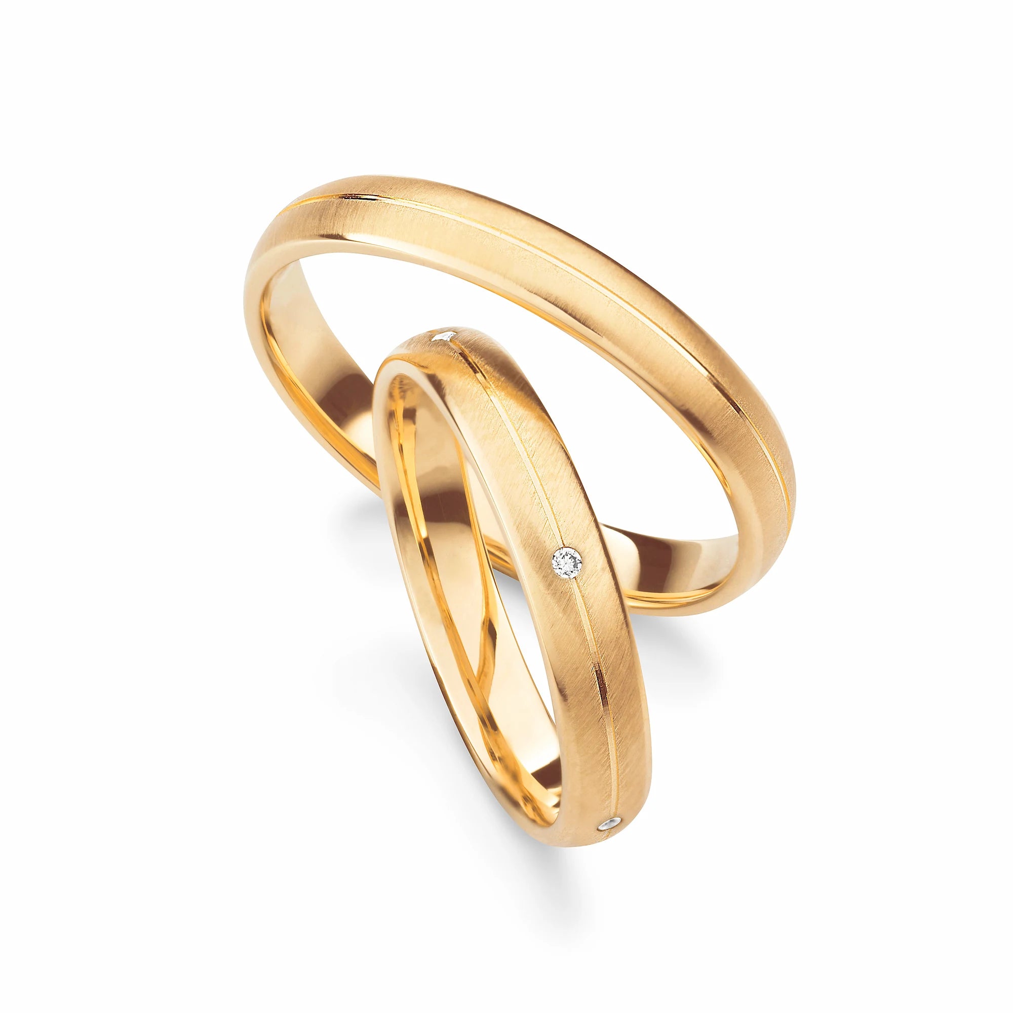 Produktfotografie des gelbgoldenen Max Kemper Trauringpaars mit einer gebürsteten Oberflächenstruktur und einer zentral eingravierten Nut und  Diamanten im Damenring