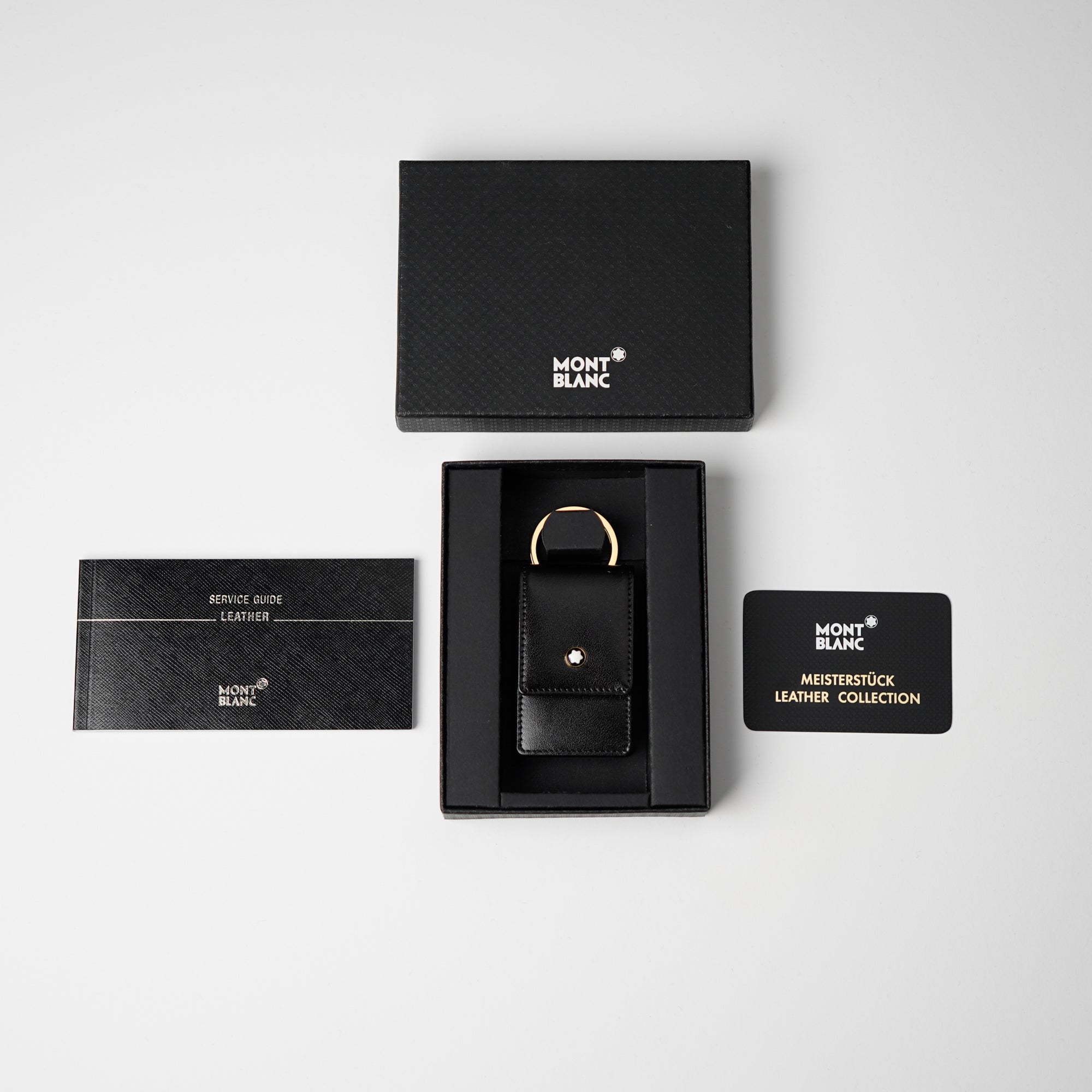 Produktfotografie des Mont Blanc Schlüsseletui in einem tief glänzendem schwarzen Leder zusammen mit dem Lieferumfang 
