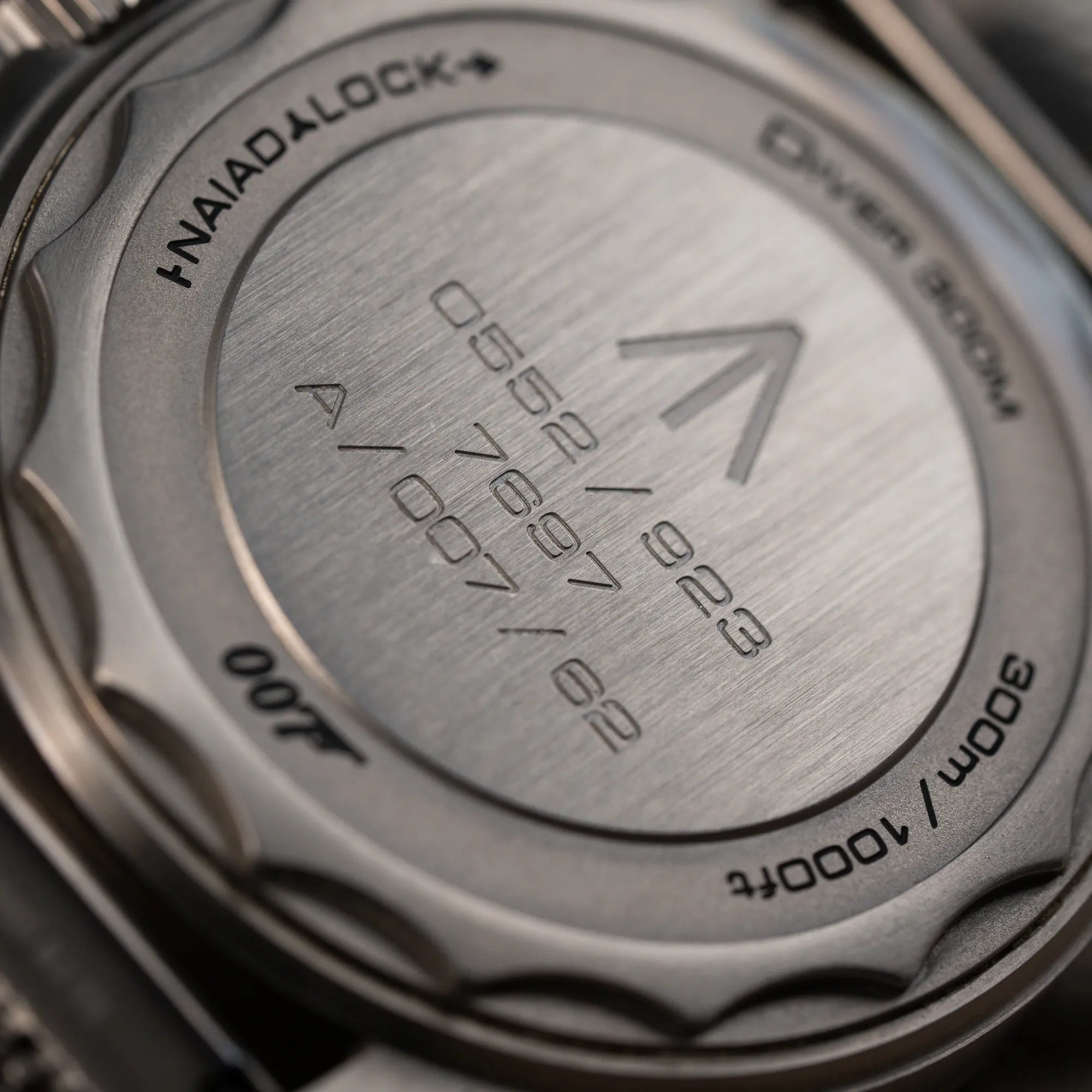 Detailaufnahme des Gehäusebodens der Omega Seamaster 300m Diver No Time To Die Limited Edition aus Titan mit braunem Zifferblatt