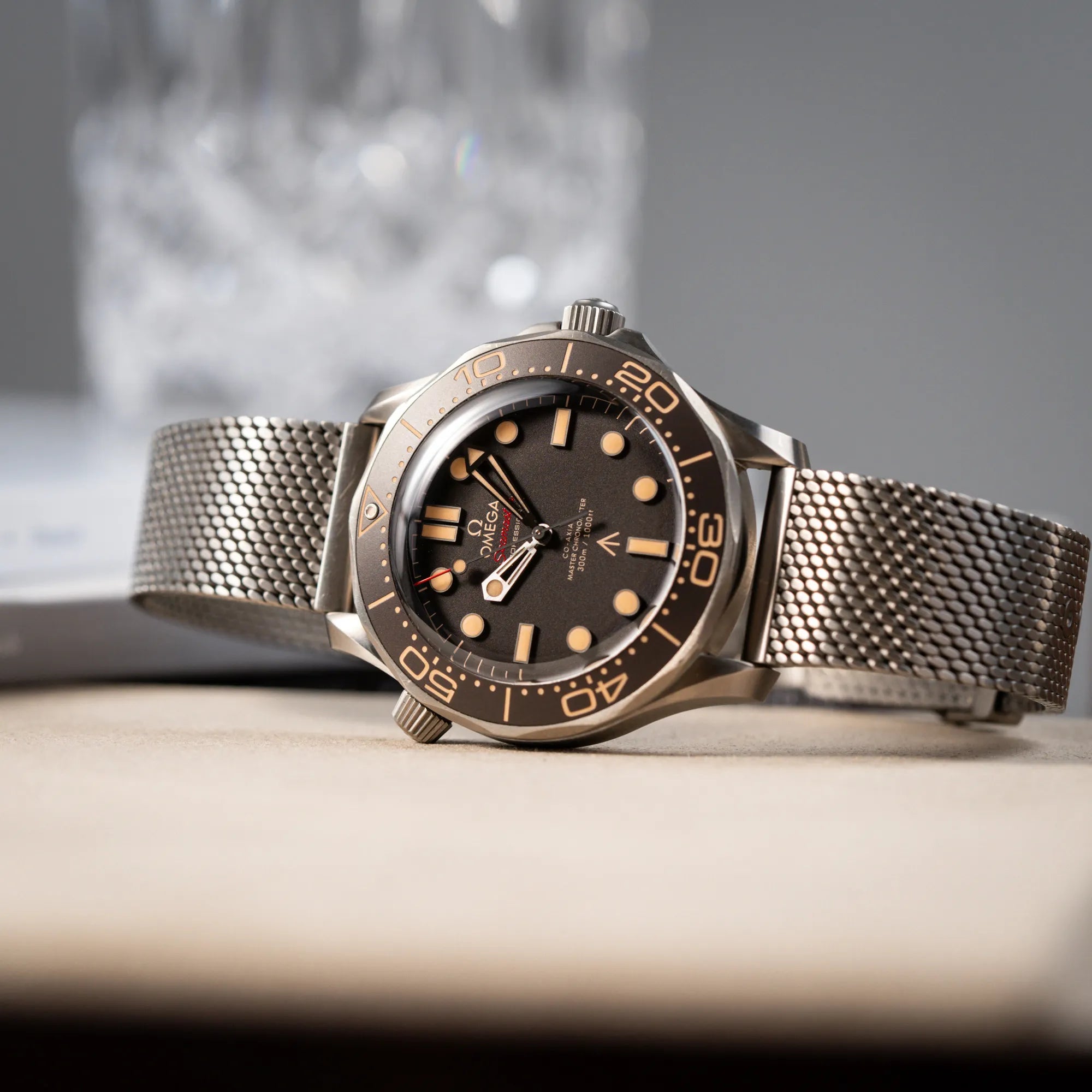 Produktfotografie der seitlich auf dem Gehäsue liegenden Omega Seamaster 300m Diver No Time To Die Limited Edition aus Titan mit braunem Zifferblatt