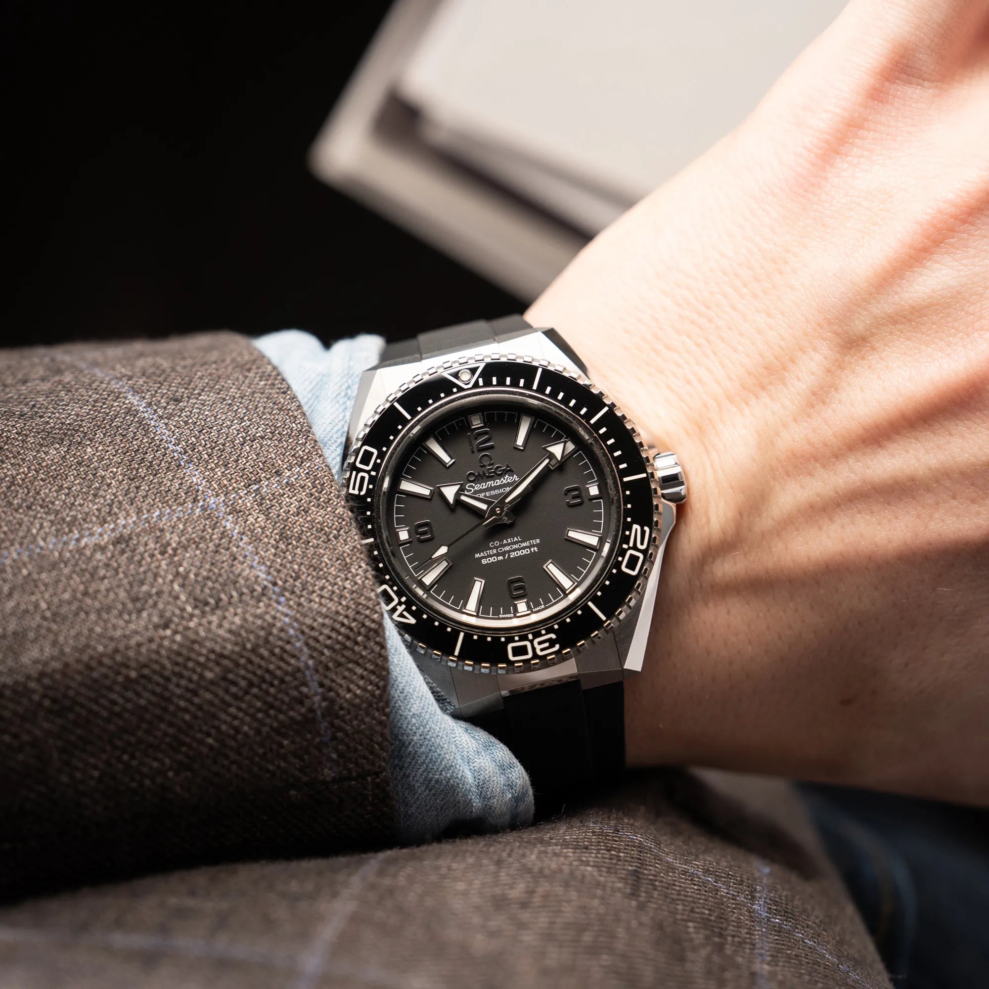 Mann trägt die Omega Seamaster Planet Ocean der Referenz 217.32.42.21.01.001 (4. Generation) mit schwarzem Zifferblatt und Lünette am schwarzen Kautschuk-Armband an seinem Handgelenk