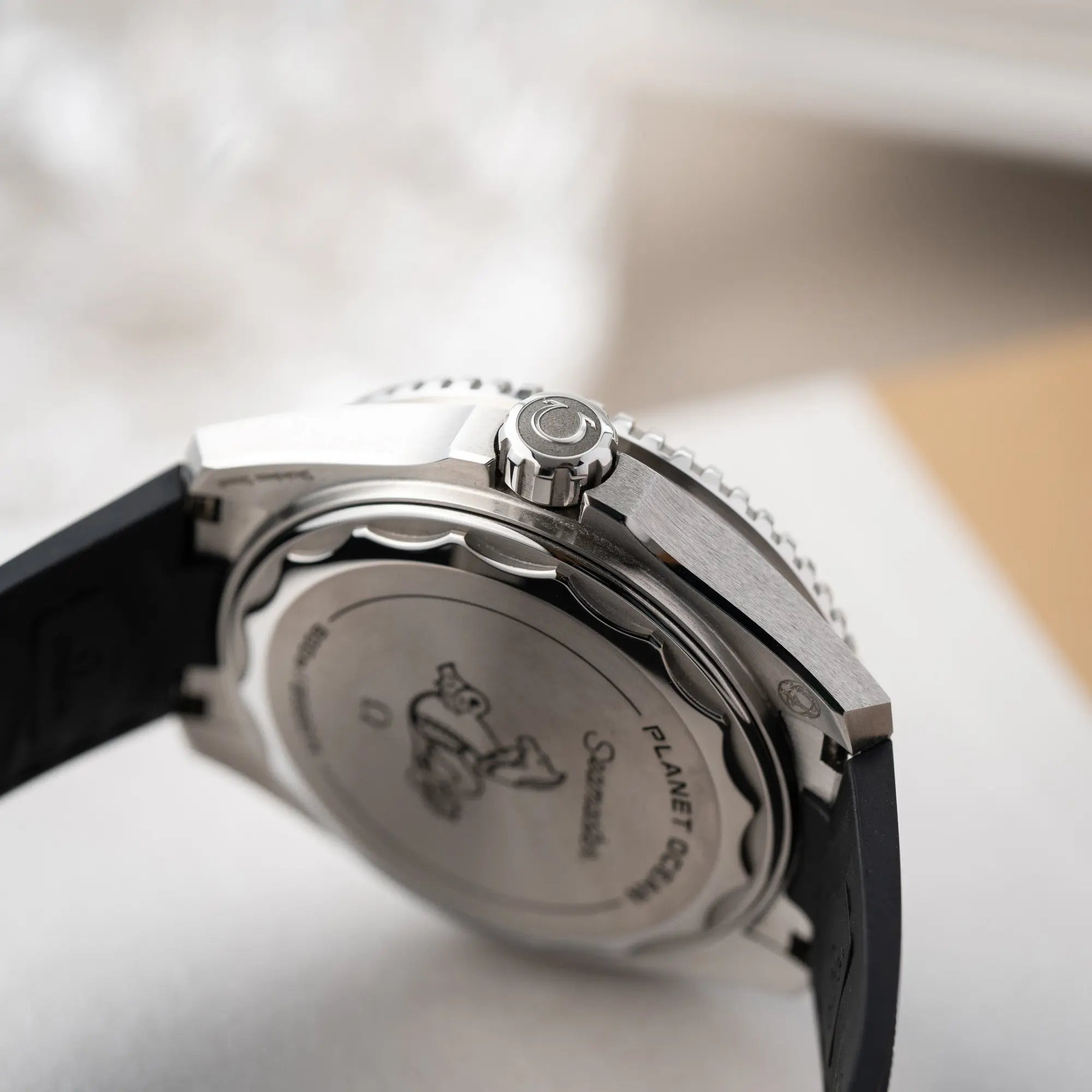 Produktfotografie zeigt die Aufzugskrone im Fokus von der Omega Seamaster Planet Ocean der Referenz 217.32.42.21.01.001 (4. Generation) mit schwarzem Zifferblatt und Lünette am schwarzen Kautschuk-Armband