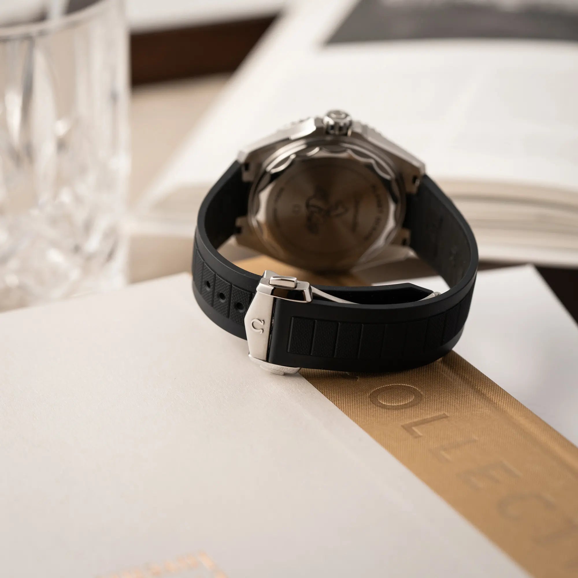 Produktfotografie der Omega Seamaster Planet Ocean der Referenz 217.32.42.21.01.001 (4. Generation) mit schwarzem Zifferblatt und Lünette am schwarzen Kautschuk-Armband zeigt die Omega-Faltschliesse