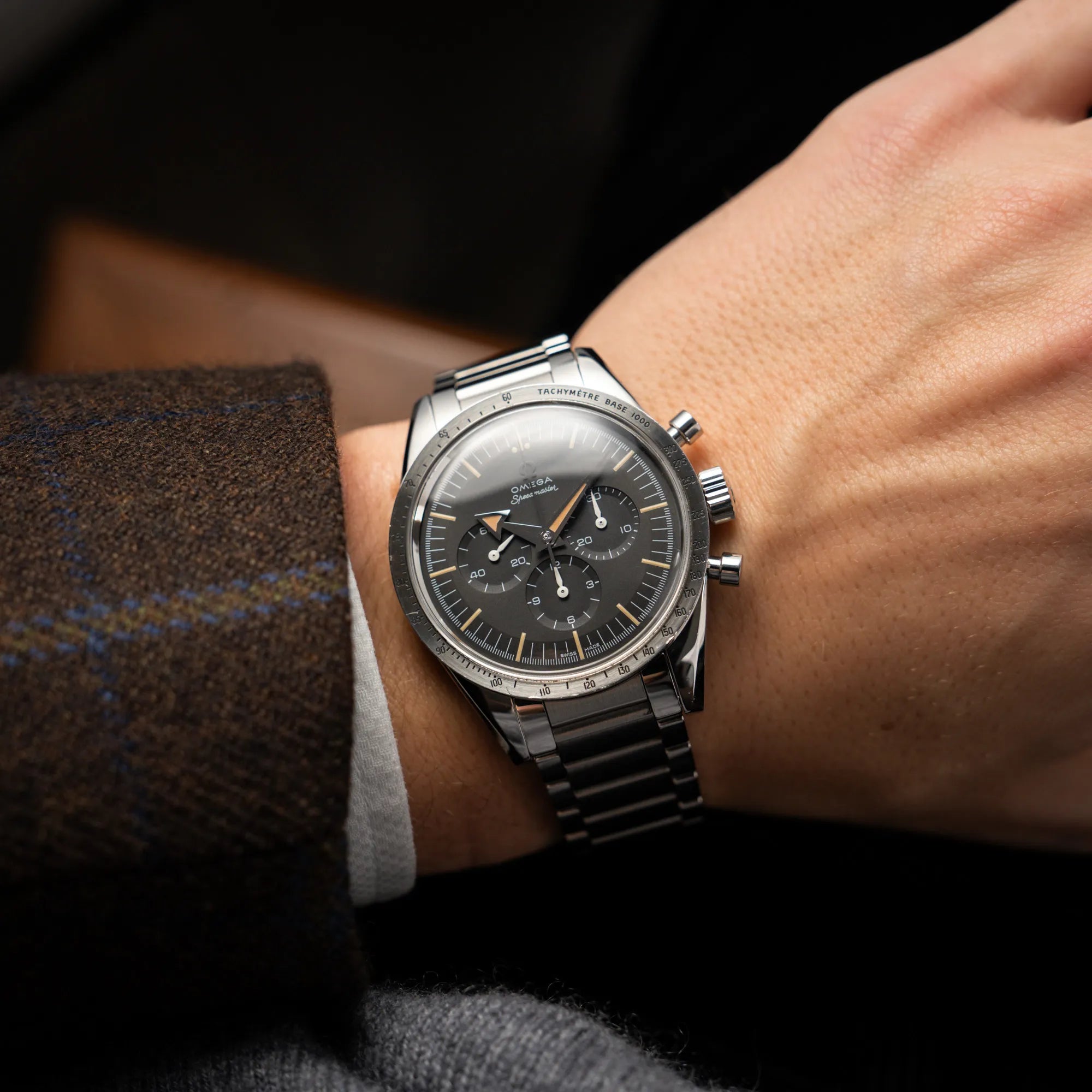 Mann trägt die Omega Speedmaster 1957 Trilogy Limited Edition mit einem anthrazitfarbenen Zifferblatt mit Vintage-Look und dem original Omega-Stahlband im Ed-White-Design für einen Wristshot an seinem Handgelenk
