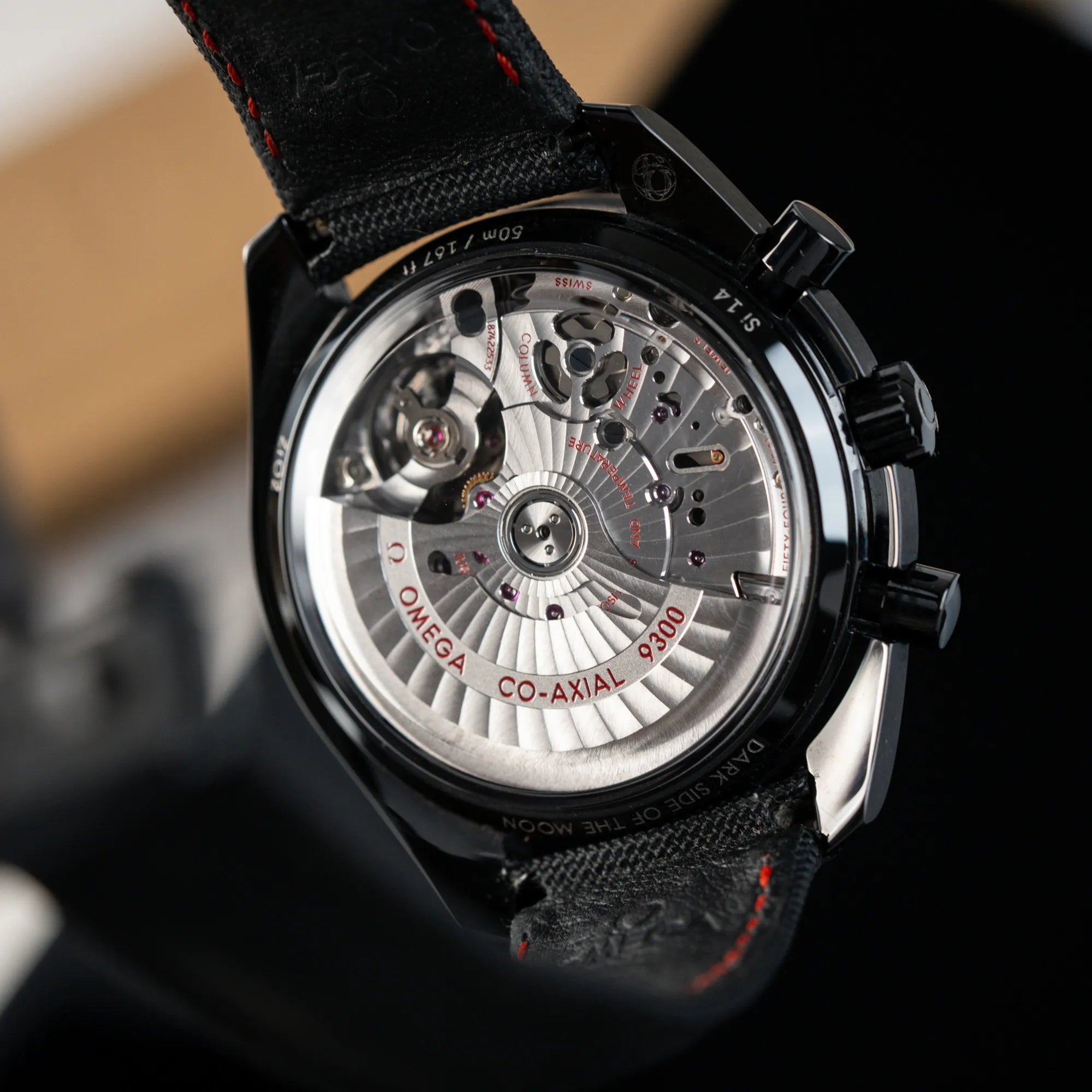 Detailaufnahme des Gehäusebodens mit Sichtglas zeigt das Automatik-Caliber 9300 von dem Omega Speedmaster "Darkside of the Moon" Chronograph mit schwarzem Zifferblatt und aus schwarzer Keramik gefertigtem Gehäuse