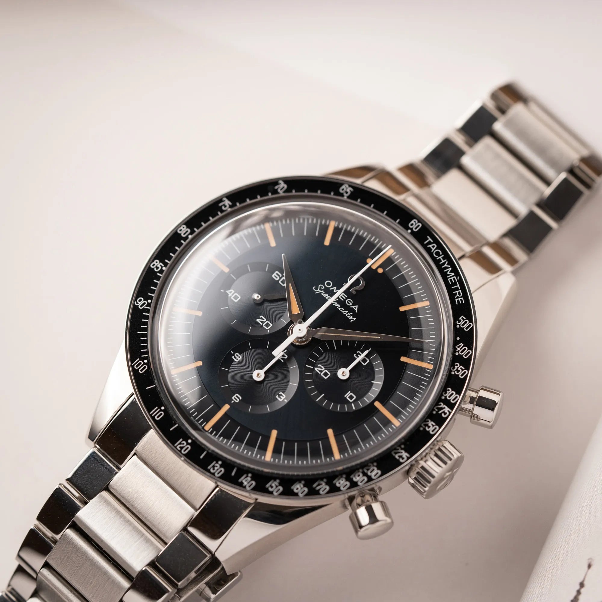 Produktfoto der Omega Speedmaster FOIS der Referenz 310.30.40.50.06.001 mit dem dunkelblauen Zifferblatt mit dunkel-beigen Indizes im Vintage-Look und einem vom Standard-Modell abgeänderten Stahl-Armband, was beides an das klassische Speedy-Modell erinnert