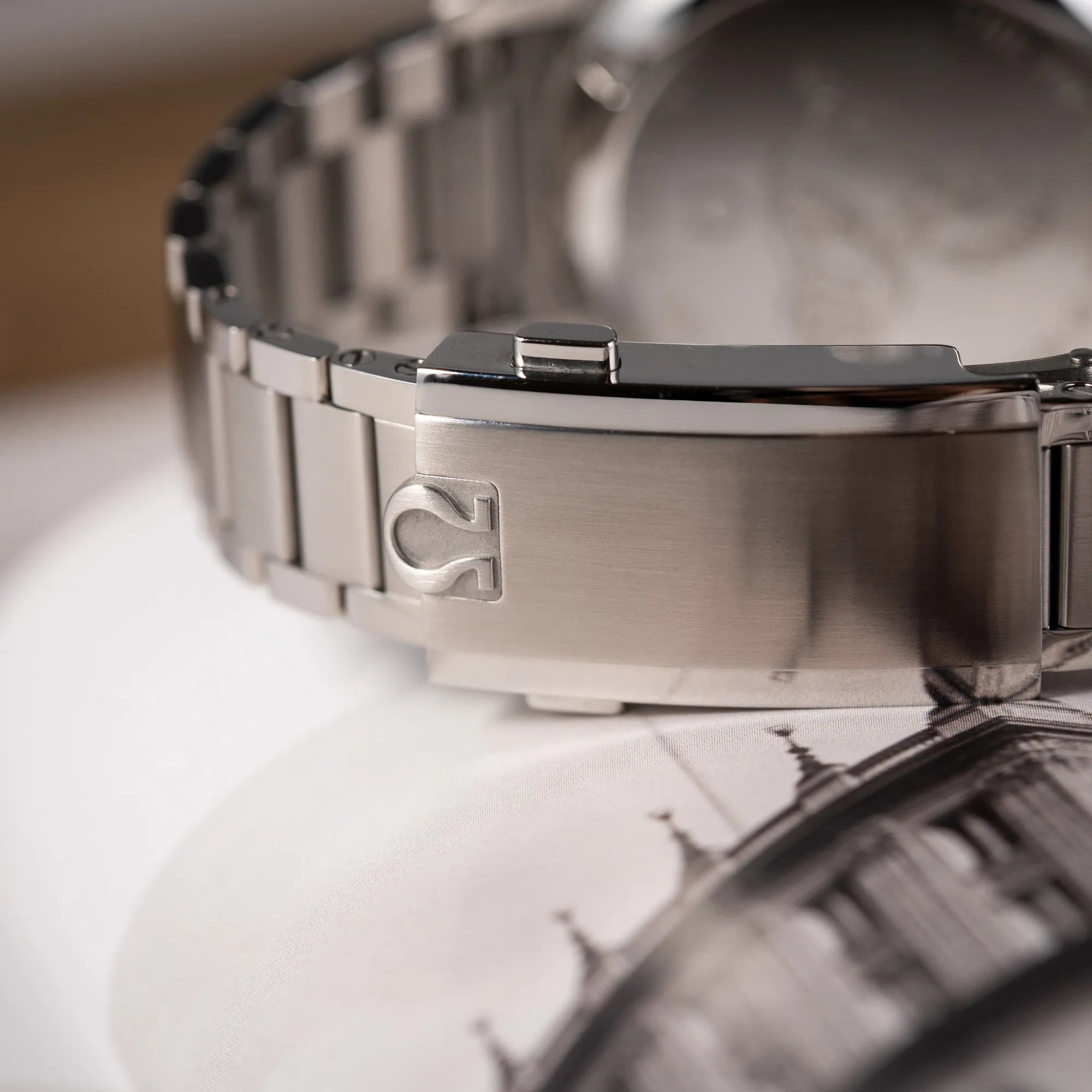 Detailaufnahme der Stahl-Faltschliesse mit Omega-Logo von der Omega Speedmaster FOIS der Referenz 310.30.40.50.06.001 mit dem dunkelblauen Zifferblatt mit dunkel-beigen Indizes im Vintage-Look und einem vom Standard-Modell abgeänderten Stahl-Armband, was beides an das klassische Speedy-Modell  erinnert