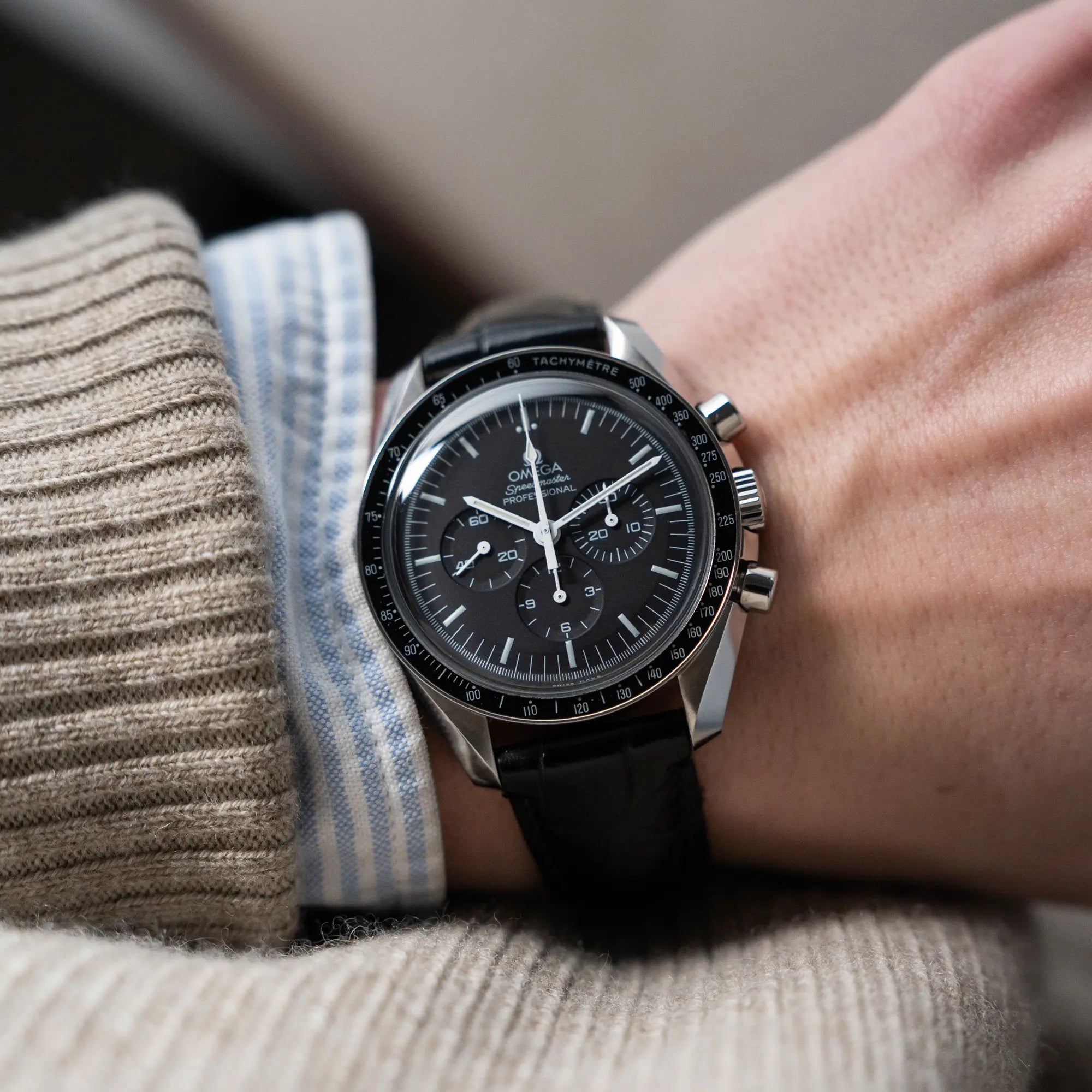 Wristshot mit der Omega Speedmaster Moonwatch am schwarzen Lederband an einem Männerhandgelenk