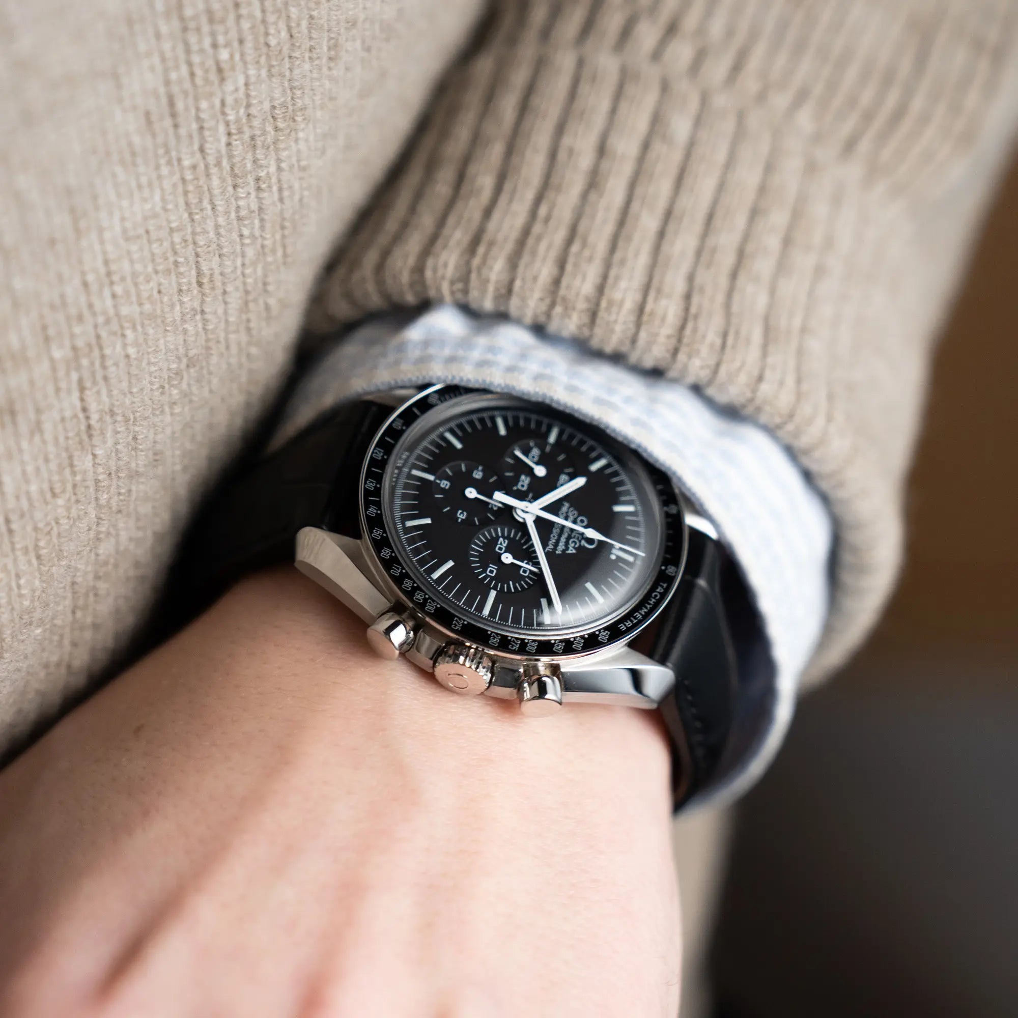 Mann trägt die Omega Speedmaster Moonwatch am schwarzen Lederband an seinem Handgelenk