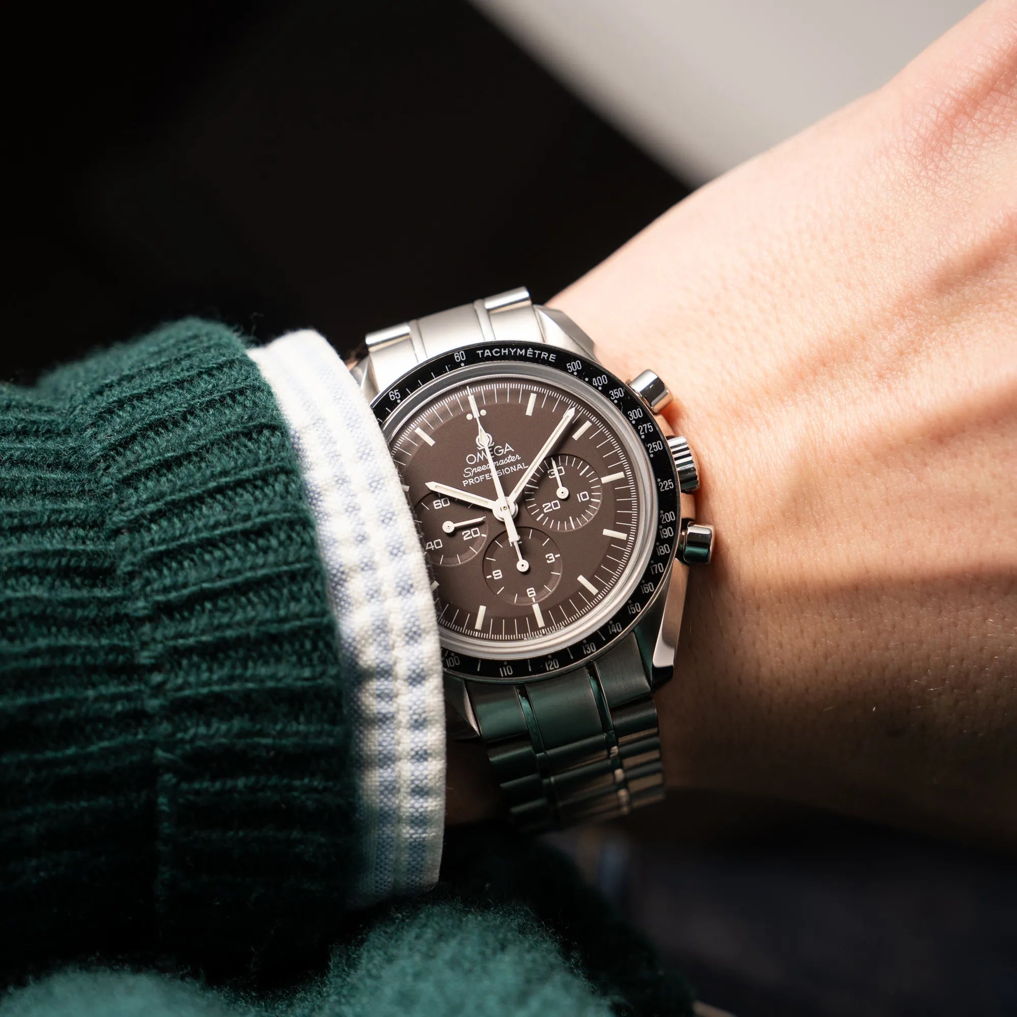 Mann trägt die Omega Speedmaster Professional Moonwatch 311.30.42.30.13.001 mit einem braunen Zifferblatt an seinem Handgelenk