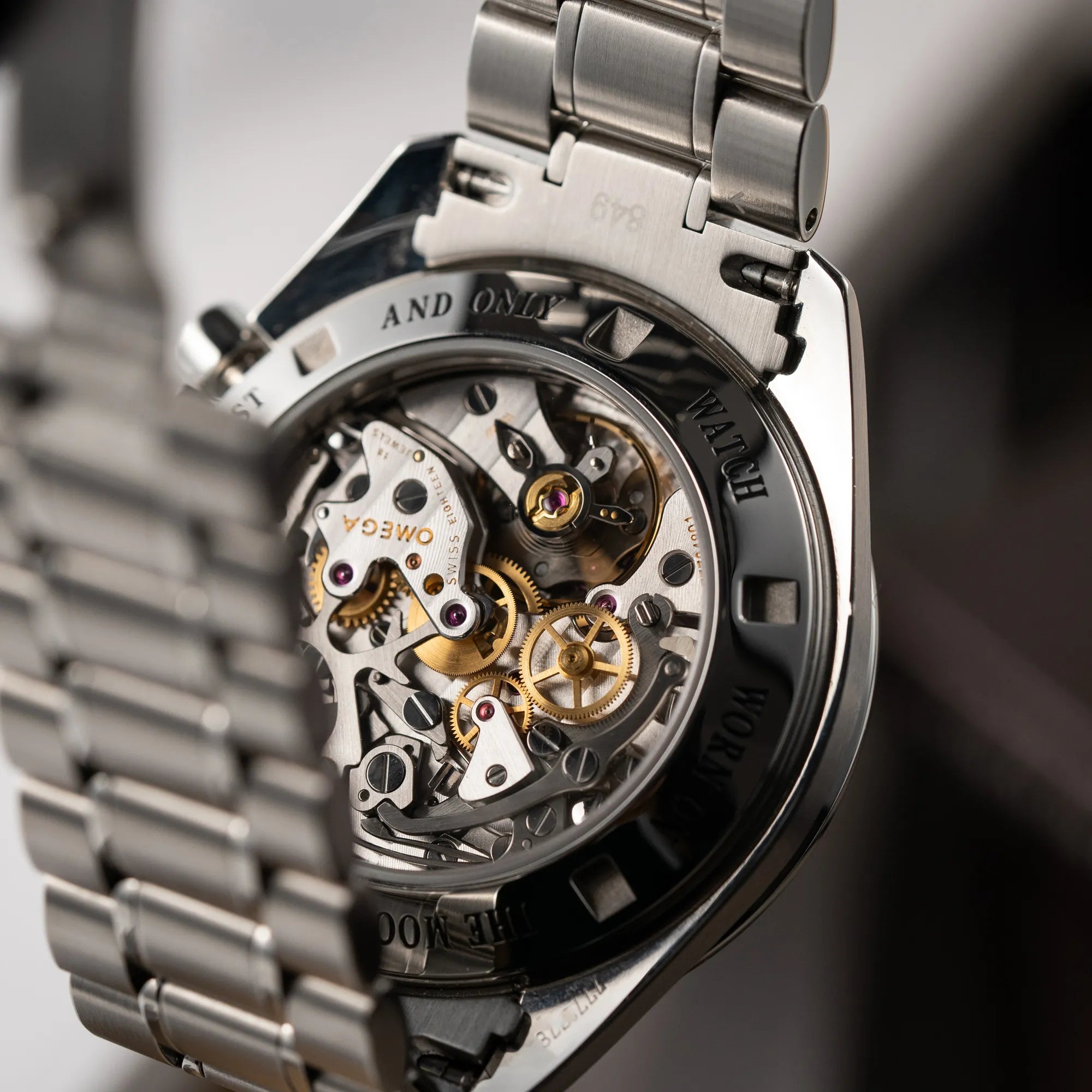 Produktfotografie der Omega Speedmaster Professional Moonwatch 311.30.42.30.13.001 mit einem braunen Zifferblatt zeigt den Gehäuseboden mit Sichtglas