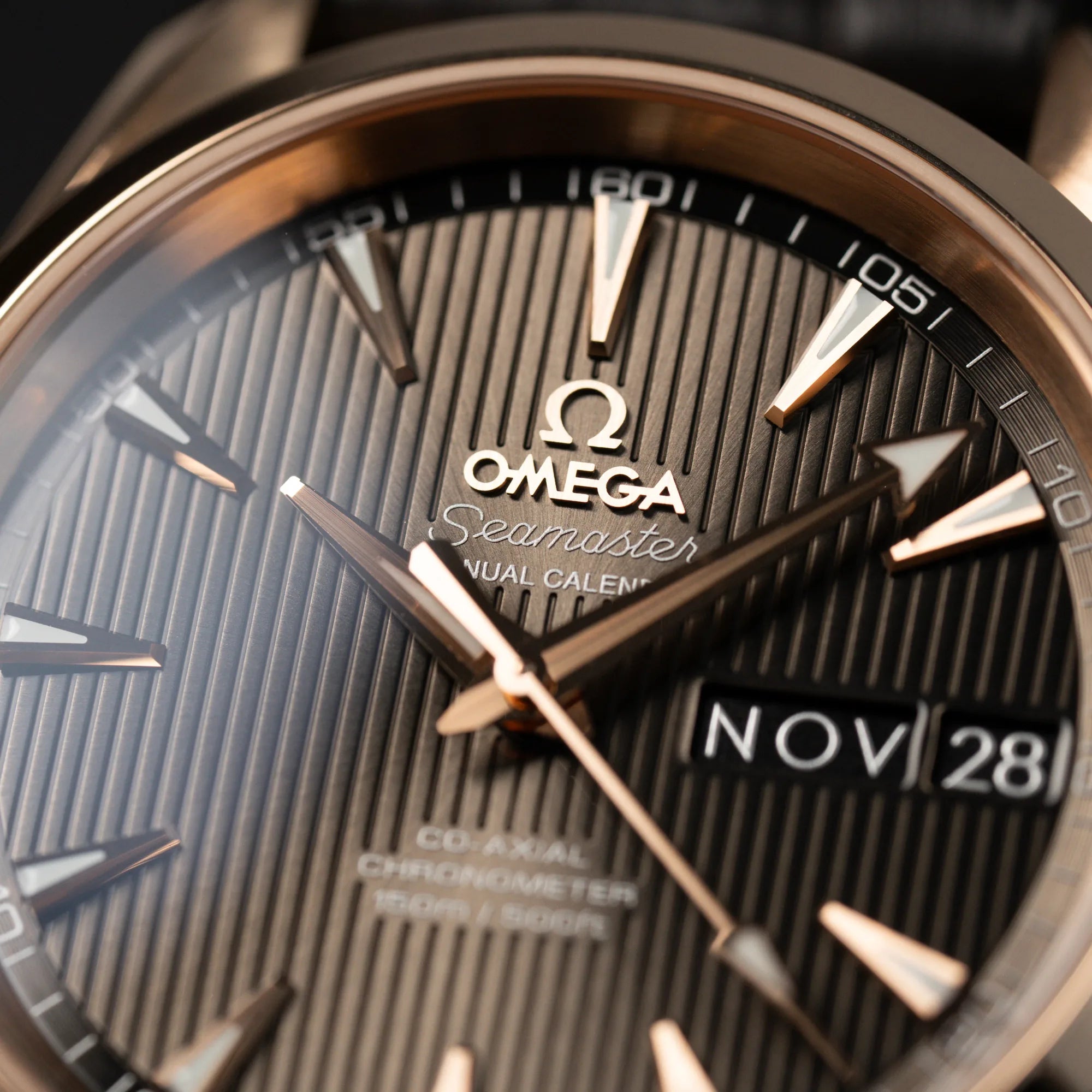 Makroaufnahme des braunen Zifferblatts mit vertikalen Linien der Omega Seamaster Aqua Terra Annual Calender mit rosségoldenem Gehäuse